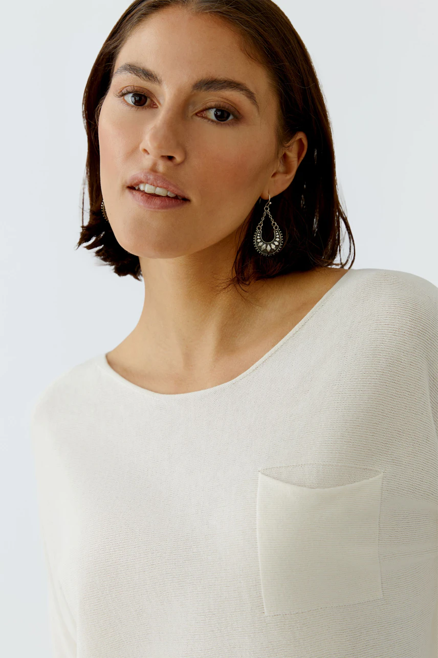 Casual women's pullover: Young woman in a light beige pullover with a pocket, looking confidently at the camera.
