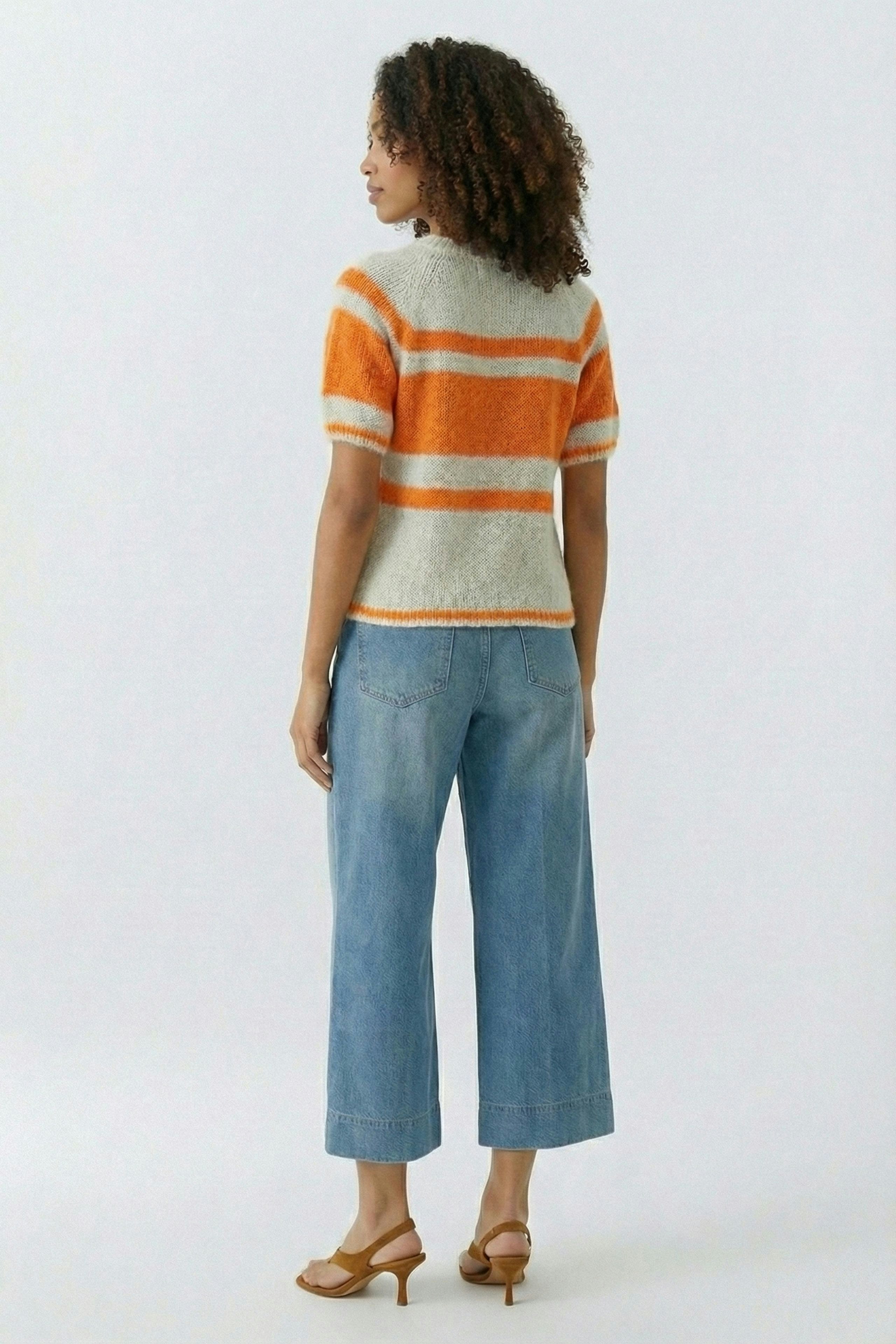 Damen-Pullover: Frau mit lockigen Haaren trägt einen gestreiften Pullover in Orange und Grau.