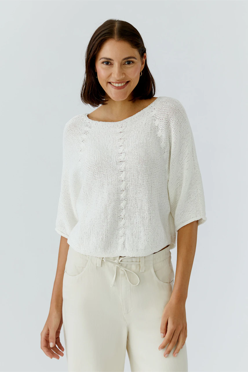 Casual women's pullover: Smiling woman in a white knitted pullover with a relaxed fit.