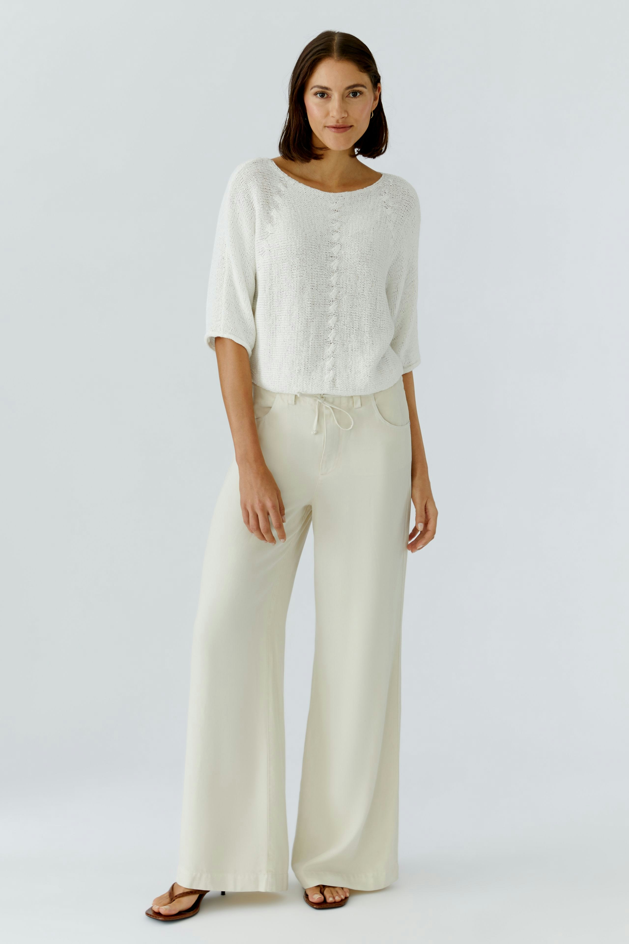 Damen-Pullover: Frau in weißem, lässigem Strickpullover mit lockerer Passform und weiten Hosen.
