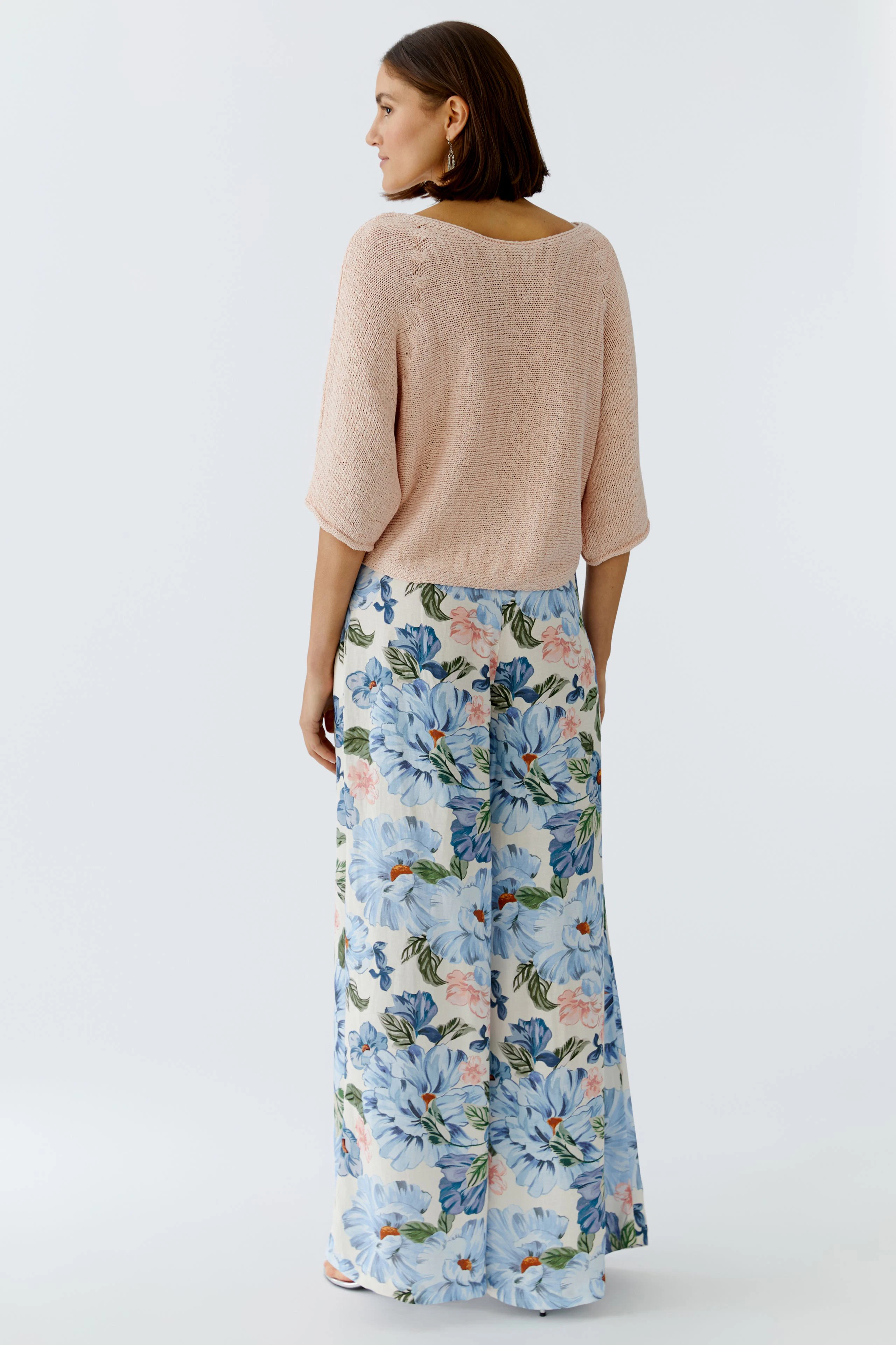 Damen-Pullover in zartem Rosé, lässig geschnitten, kombiniert mit floralen Hosen.