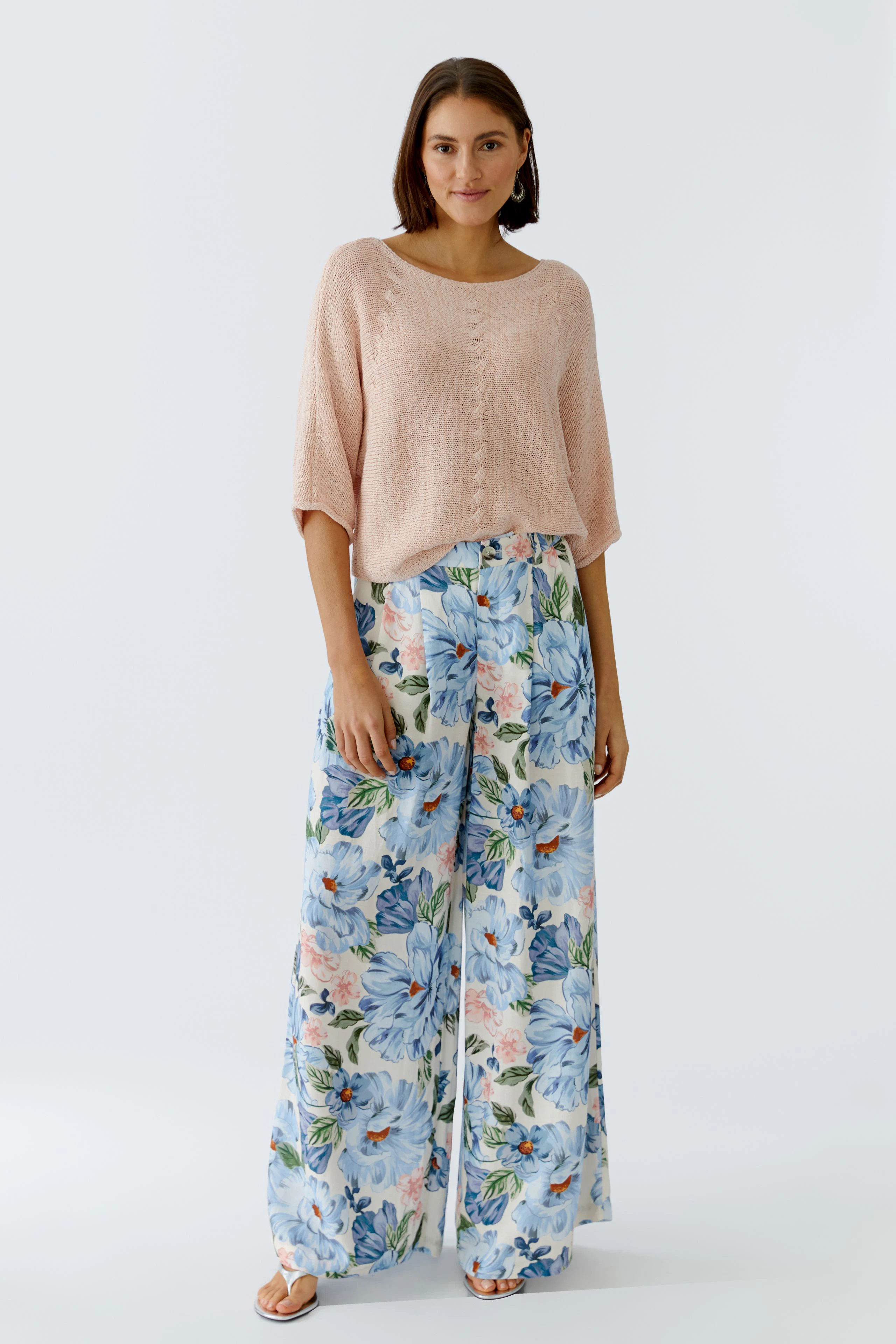 Leichter Damen-Pullover in zartem Rosa, kombiniert mit floralen, weiten Hosen.
