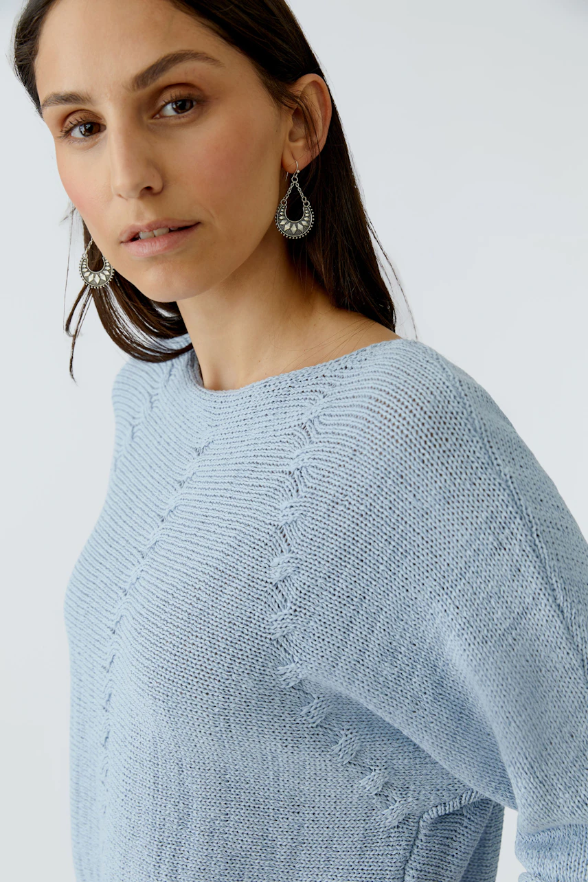 Light blue pullover: Woman wearing a relaxed-fit pullover with a textured knit design.