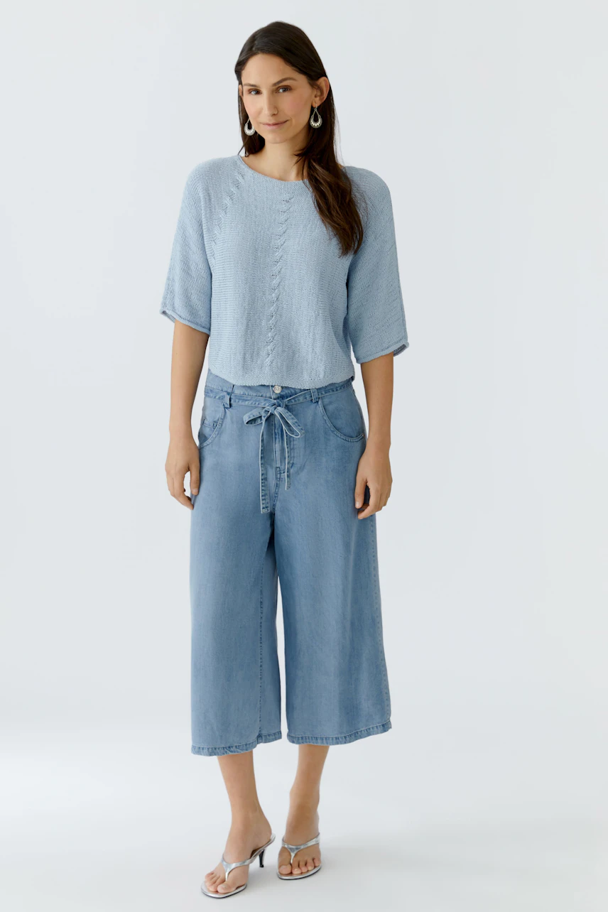 Casual women's pullover: A woman in a light blue knitted pullover paired with wide denim pants.