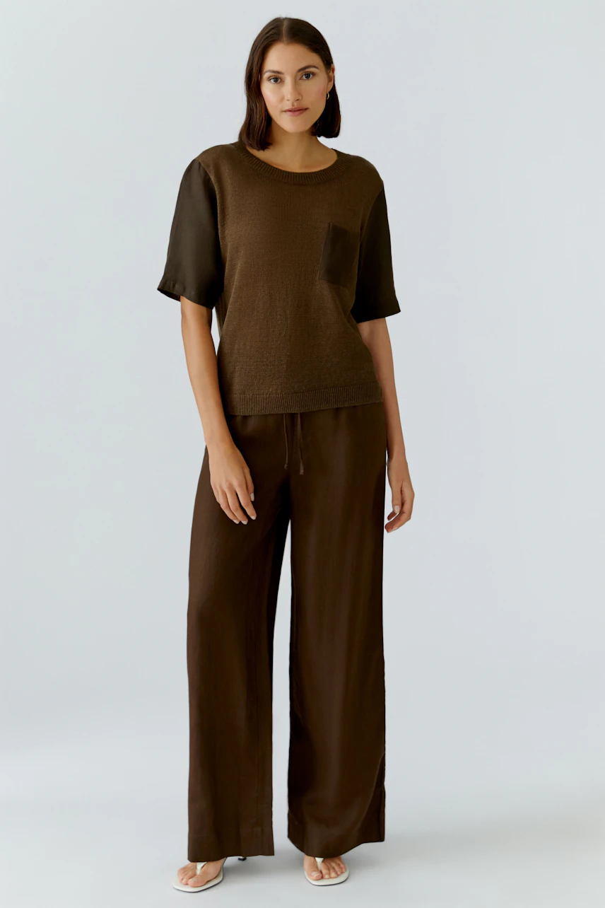 Casual women's pullover: A woman in a brown pullover with a pocket, paired with relaxed-fit pants.