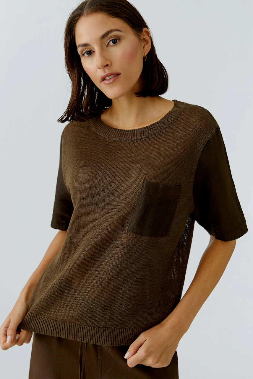 Casual women's pullover: A woman in a brown pullover with short sleeves and a chest pocket, looking relaxed.
