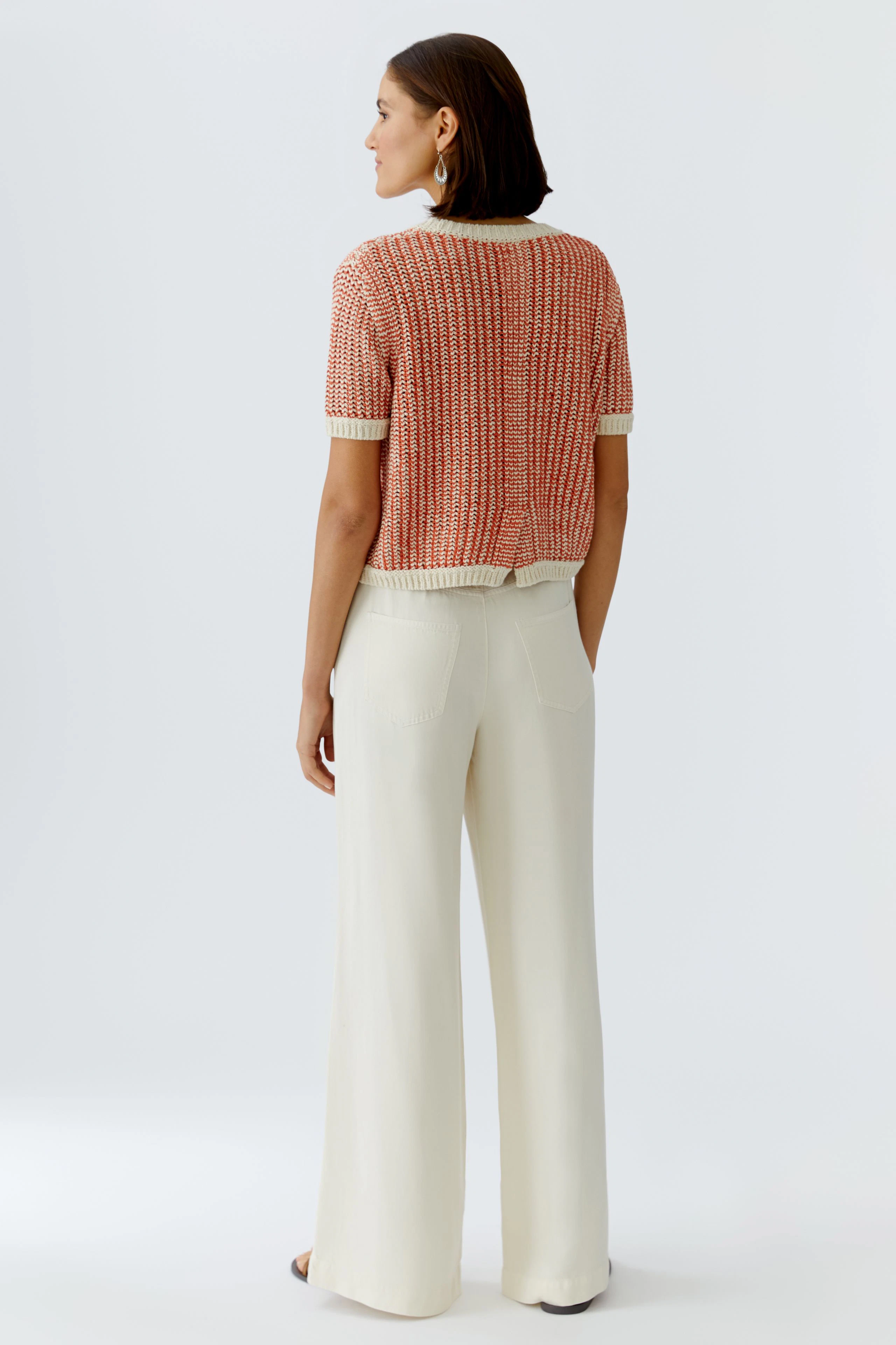 Casual women's pullover: A woman in a short-sleeved, red and white knit pullover with wide trousers.
