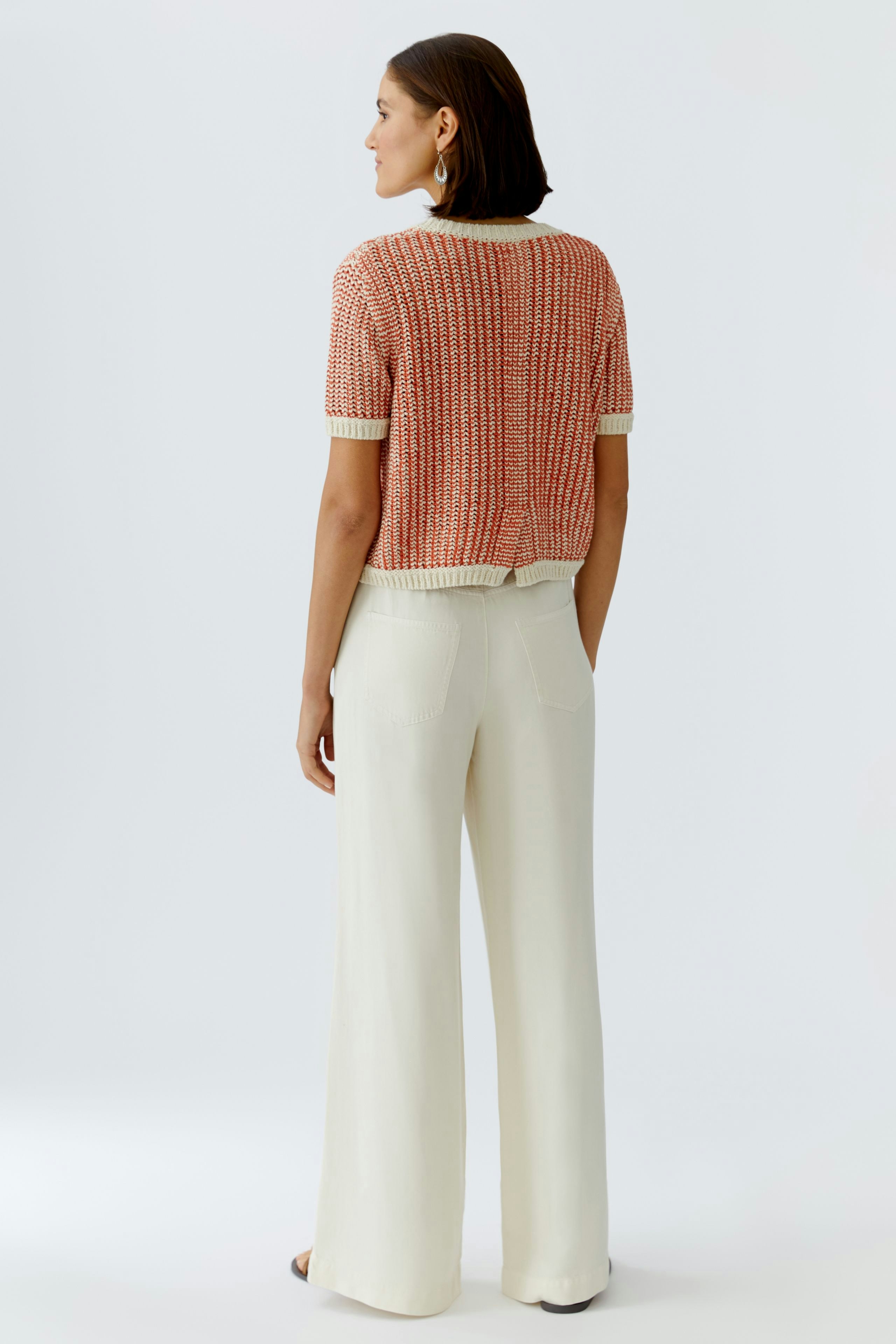 Casual women's pullover: A woman in a short-sleeved, red and white knit pullover with wide trousers.