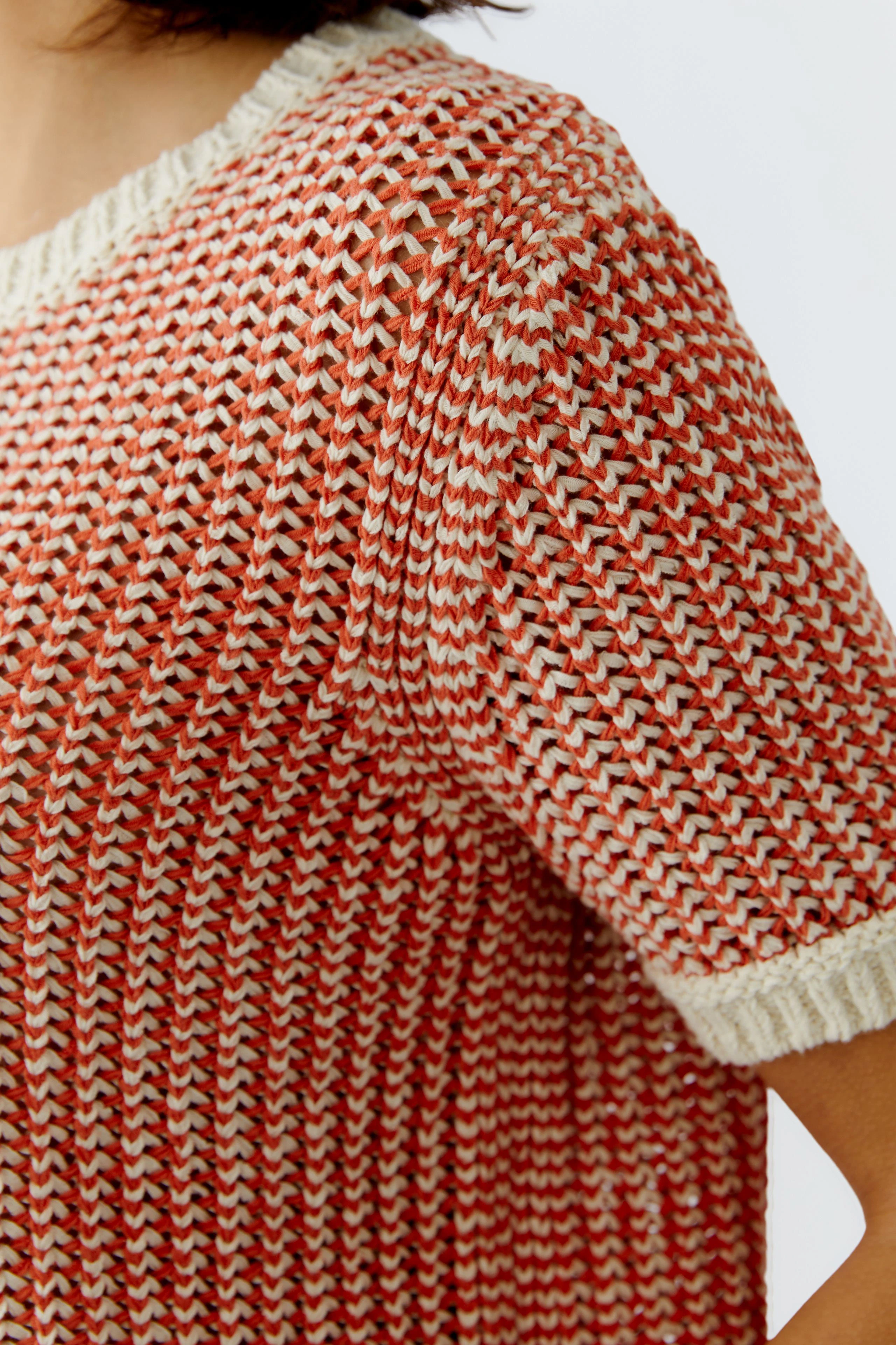 Casual women's pullover: Close-up of a woman in a red and cream knitted pullover with short sleeves.