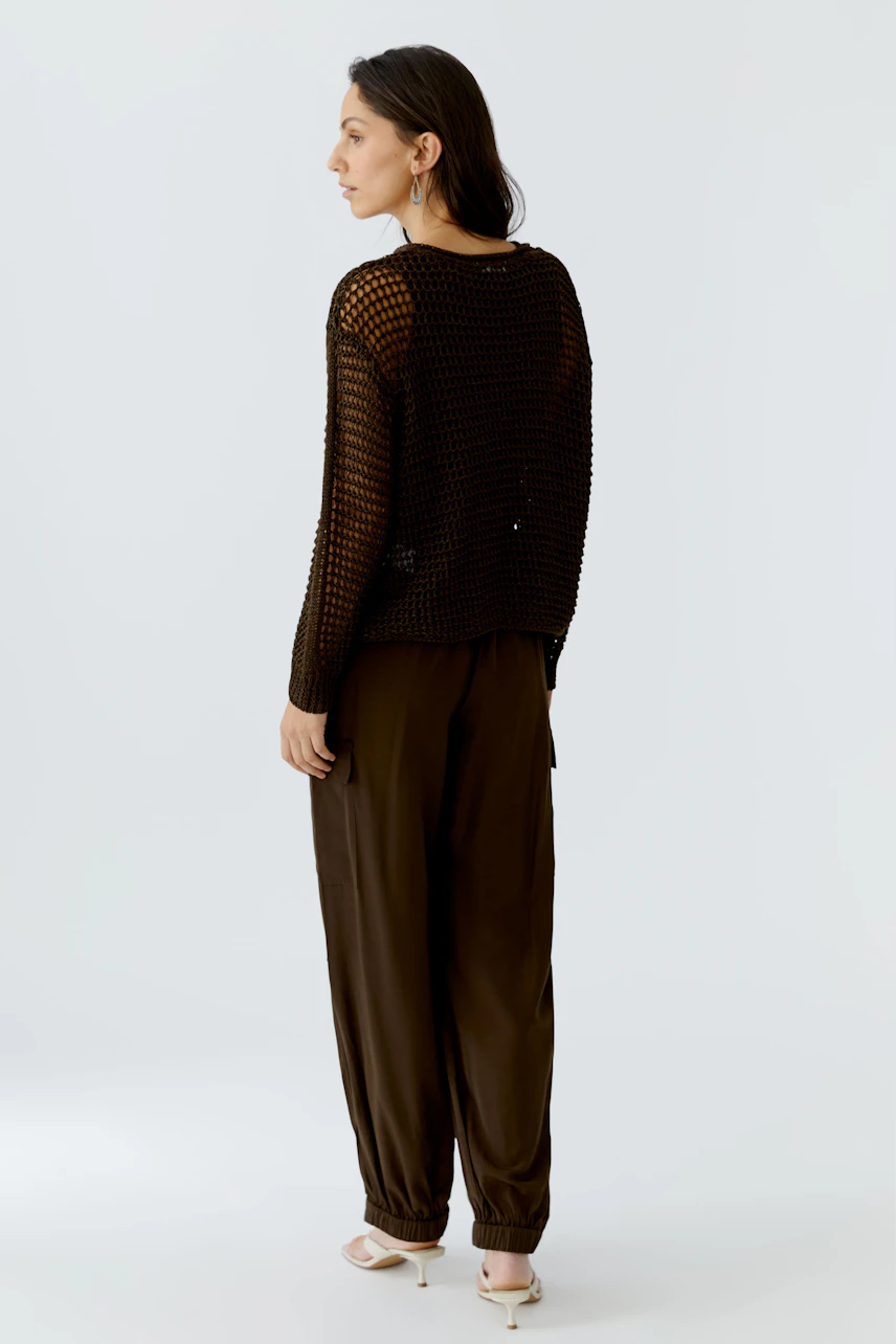 Casual women's pullover: A woman in a black open-knit pullover paired with relaxed trousers.