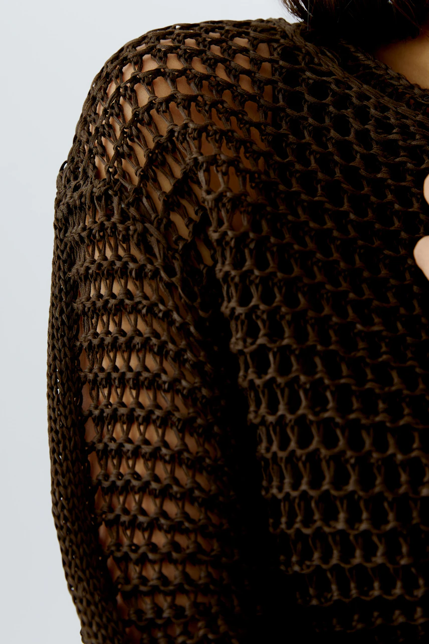 Casual women's pullover: Close-up of a woman wearing a brown, open-knit pullover with a relaxed fit.