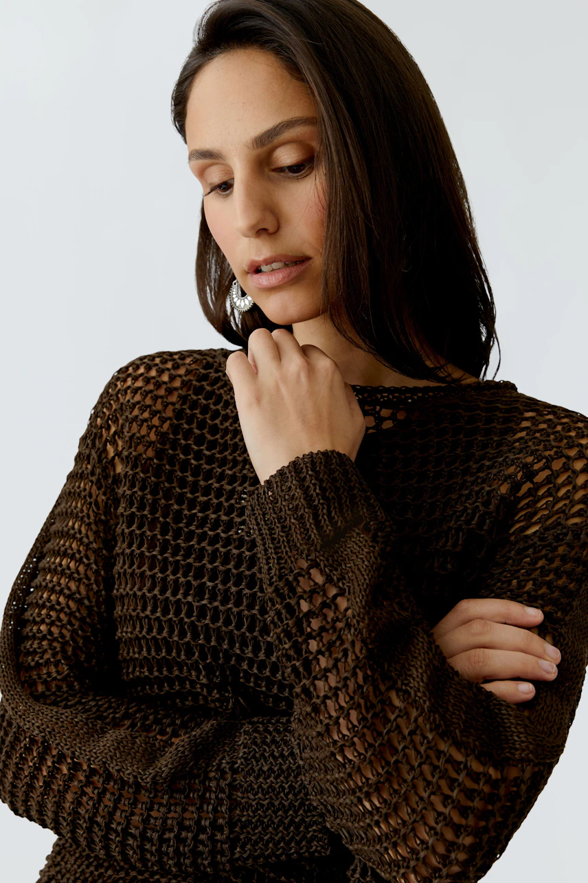 Modern women's pullover: A woman in a brown knitted pullover with a relaxed fit.