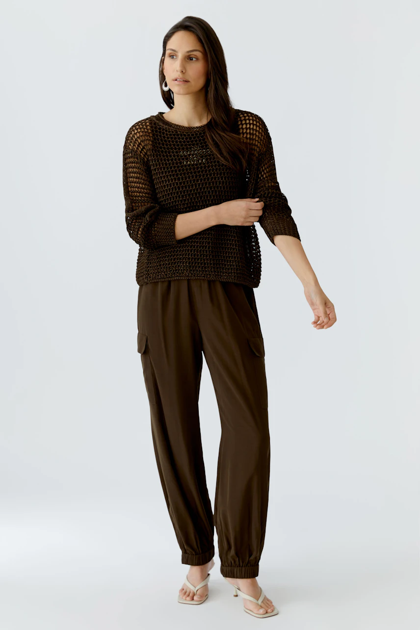 Casual women's pullover: A woman in a brown knitted pullover with a relaxed fit and stylish pants.
