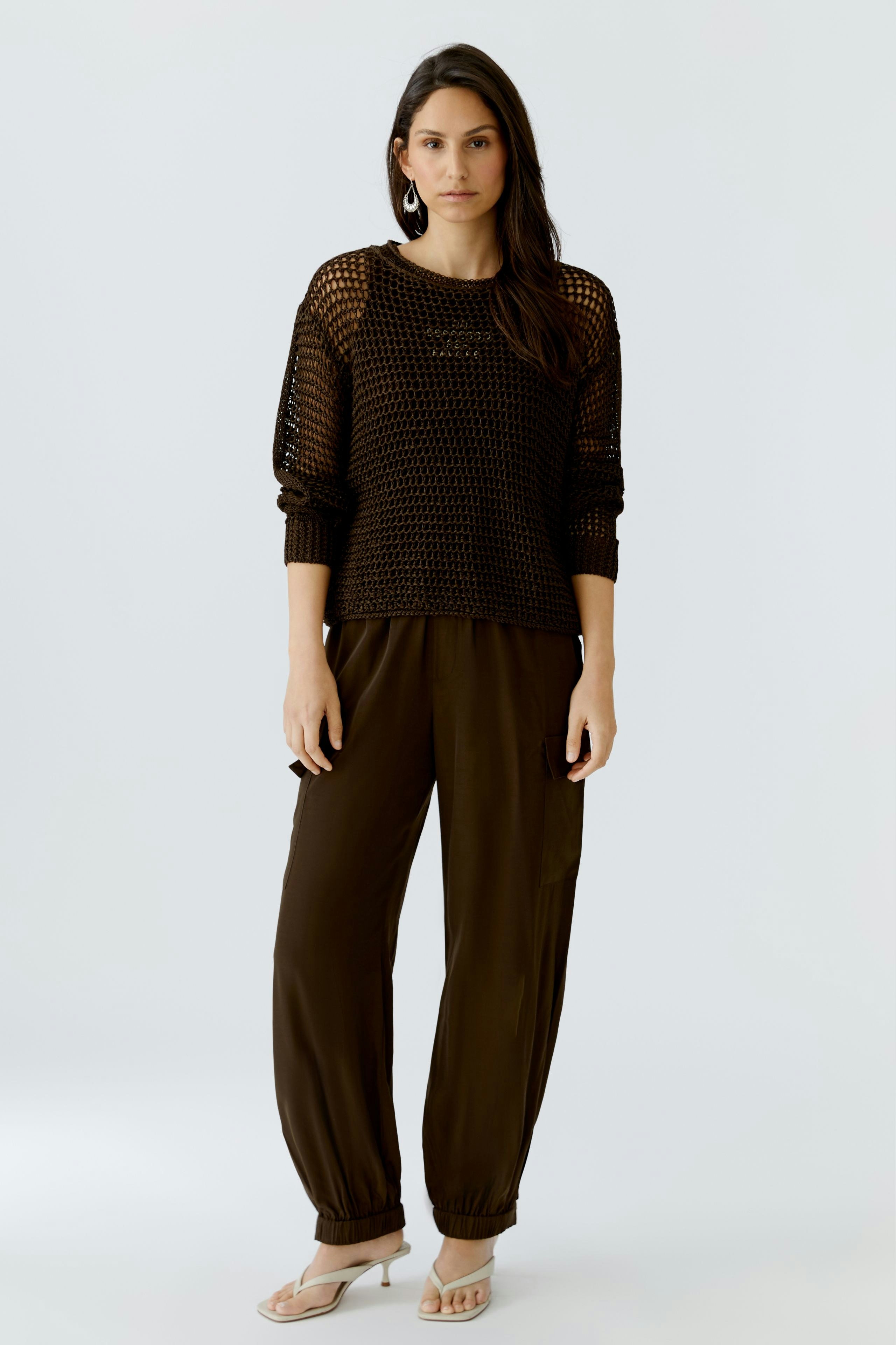 Damen-Pullover: Frau in schwarzem, luftigen Strickpullover mit lässigem Schnitt und bequemen Hosen.