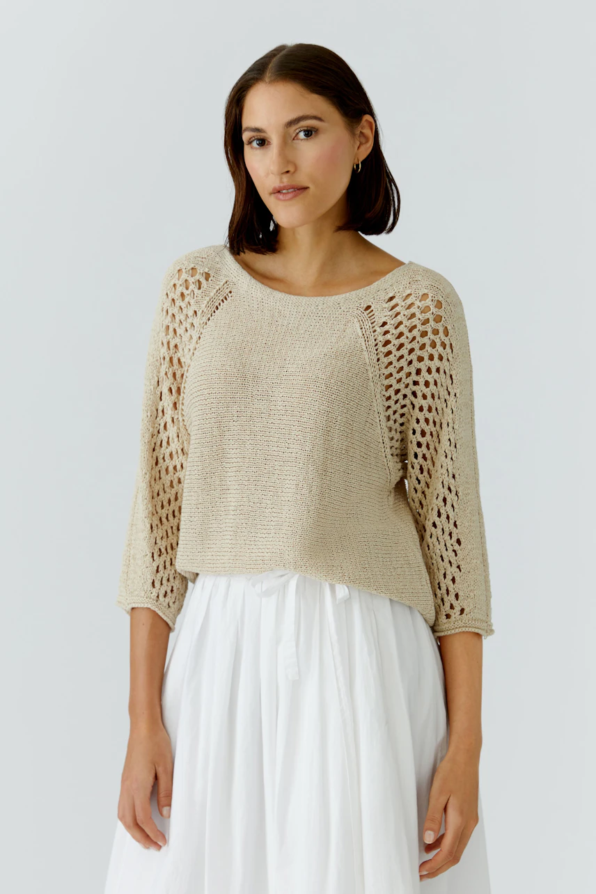 Casual women's pullover: A woman in a light beige knitted pullover with openwork details.