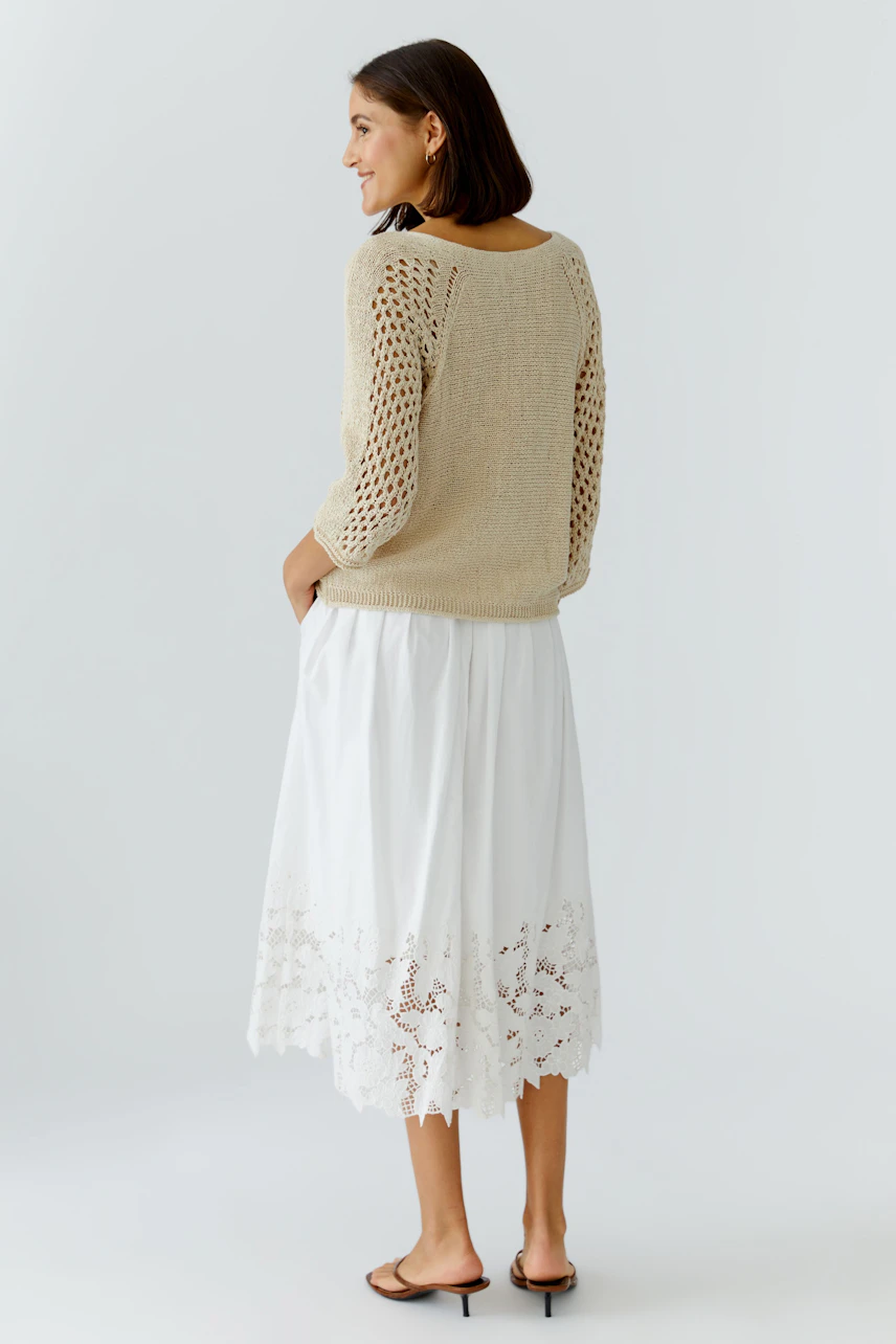 Casual women's pullover: A woman in a light knit pullover with openwork details, paired with a flowy white skirt.