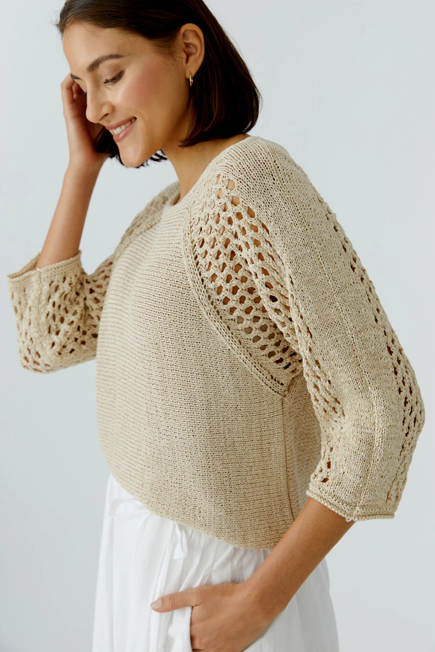 Casual women's pullover: A woman smiles while wearing a beige knitted pullover with openwork sleeves.