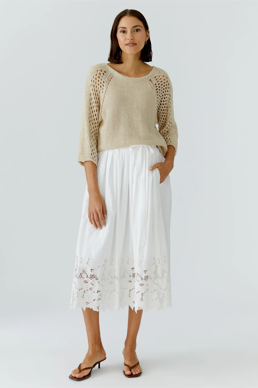 Casual women's pullover: A woman in a light knit pullover with openwork sleeves and a relaxed fit.