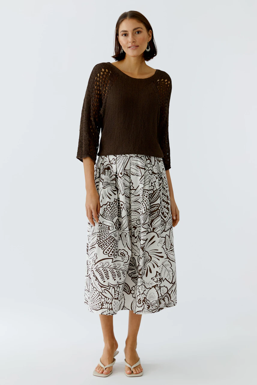 Casual women's pullover: A woman in a brown knitted pullover paired with a floral skirt.
