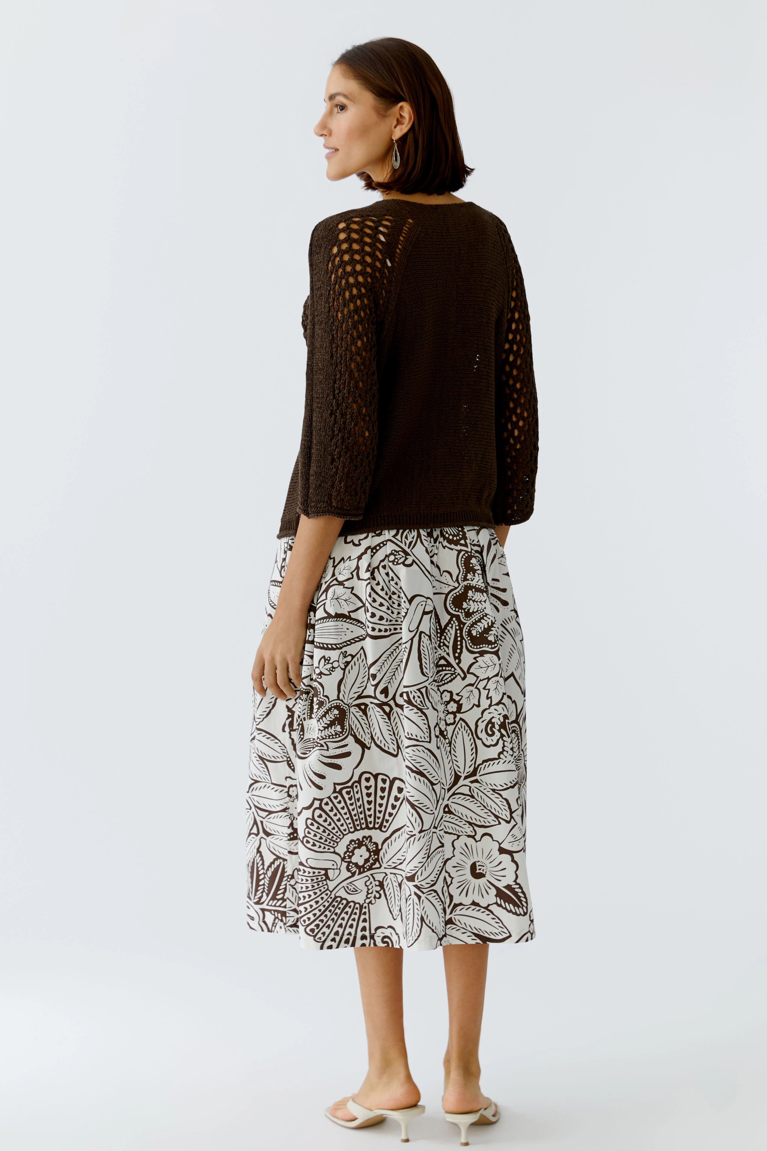 Damen-Pullover: Frau in braunem, luftigen Strickpullover mit weitem Schnitt und floralem Rock.