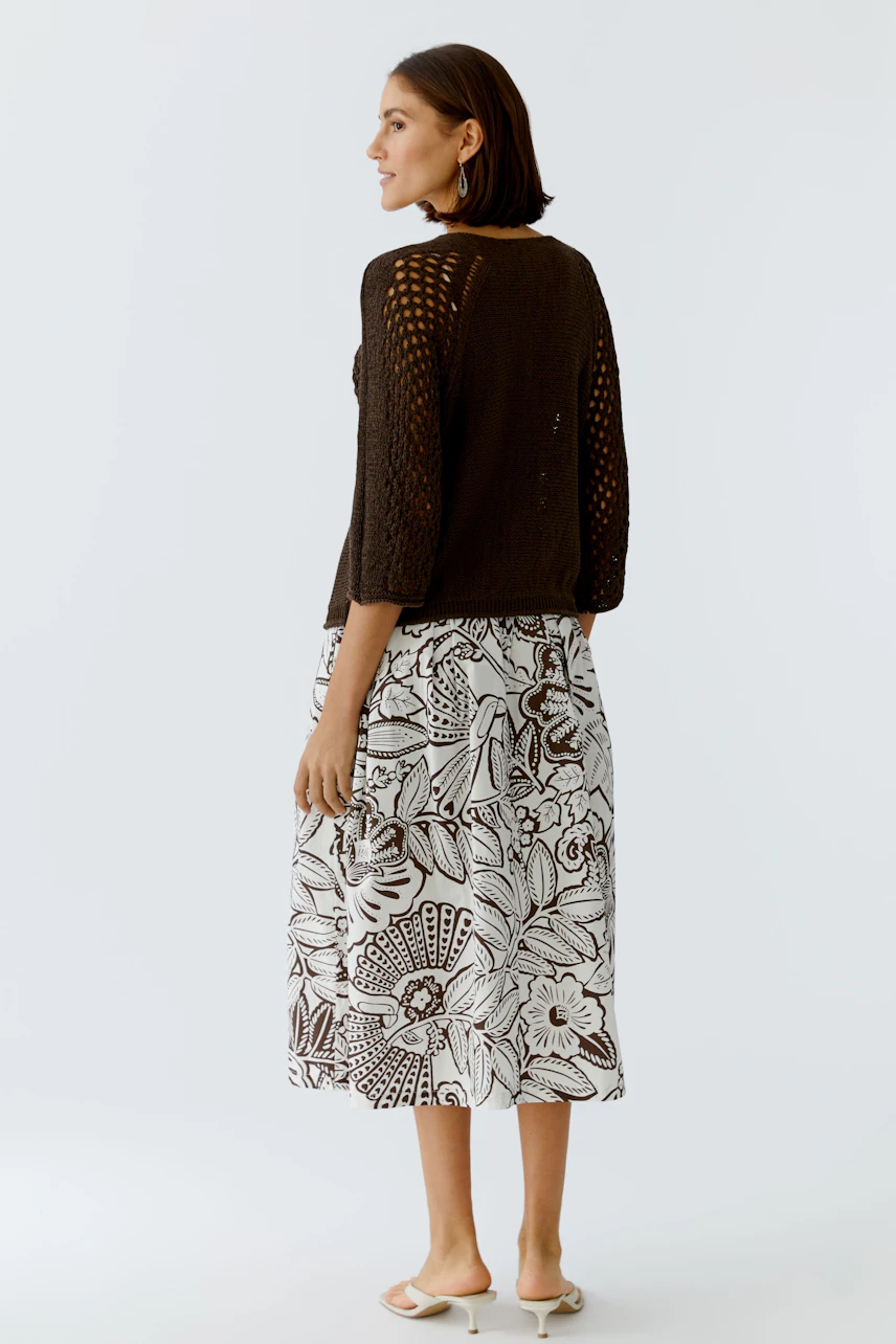 Casual women's pullover: A woman in a brown knitted pullover with a relaxed fit, paired with a floral skirt.