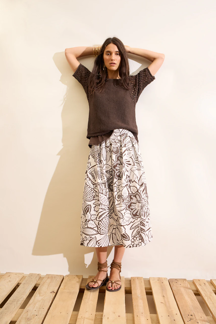 Casual women's pullover: Woman in a brown pullover with a floral skirt, standing confidently.