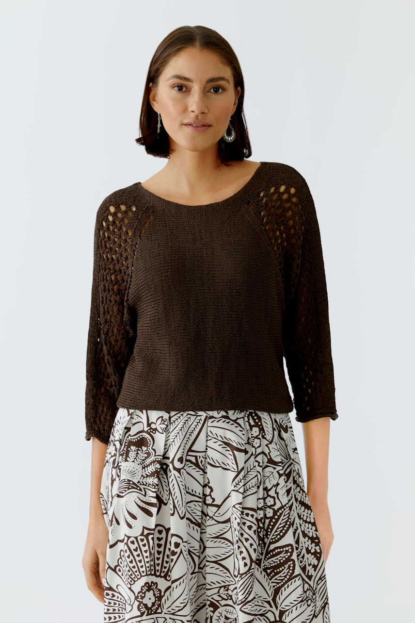 Casual women's pullover: A woman in a brown knitted pullover with openwork details, paired with a patterned skirt.