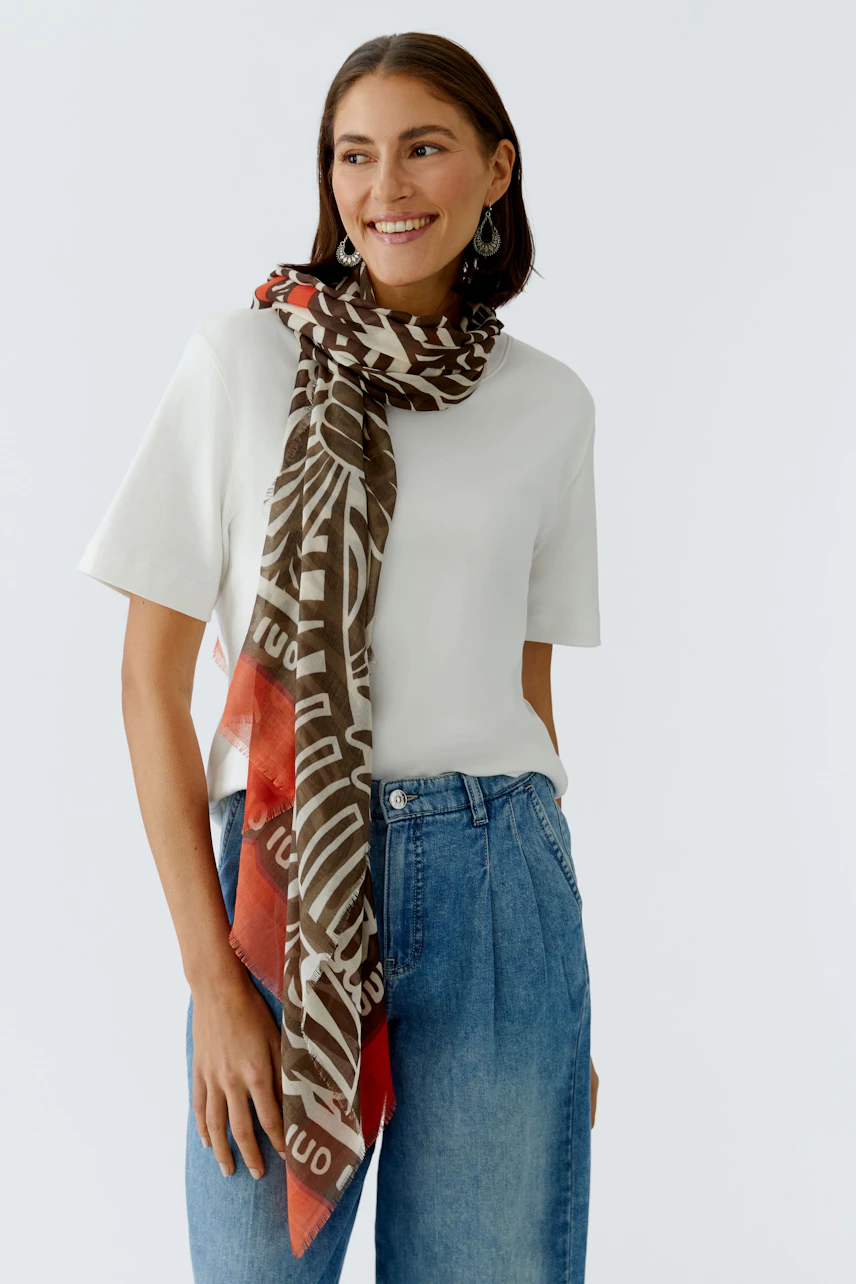 Stylish women's scarf: A woman wearing a patterned scarf with earthy tones, paired with a simple tee.
