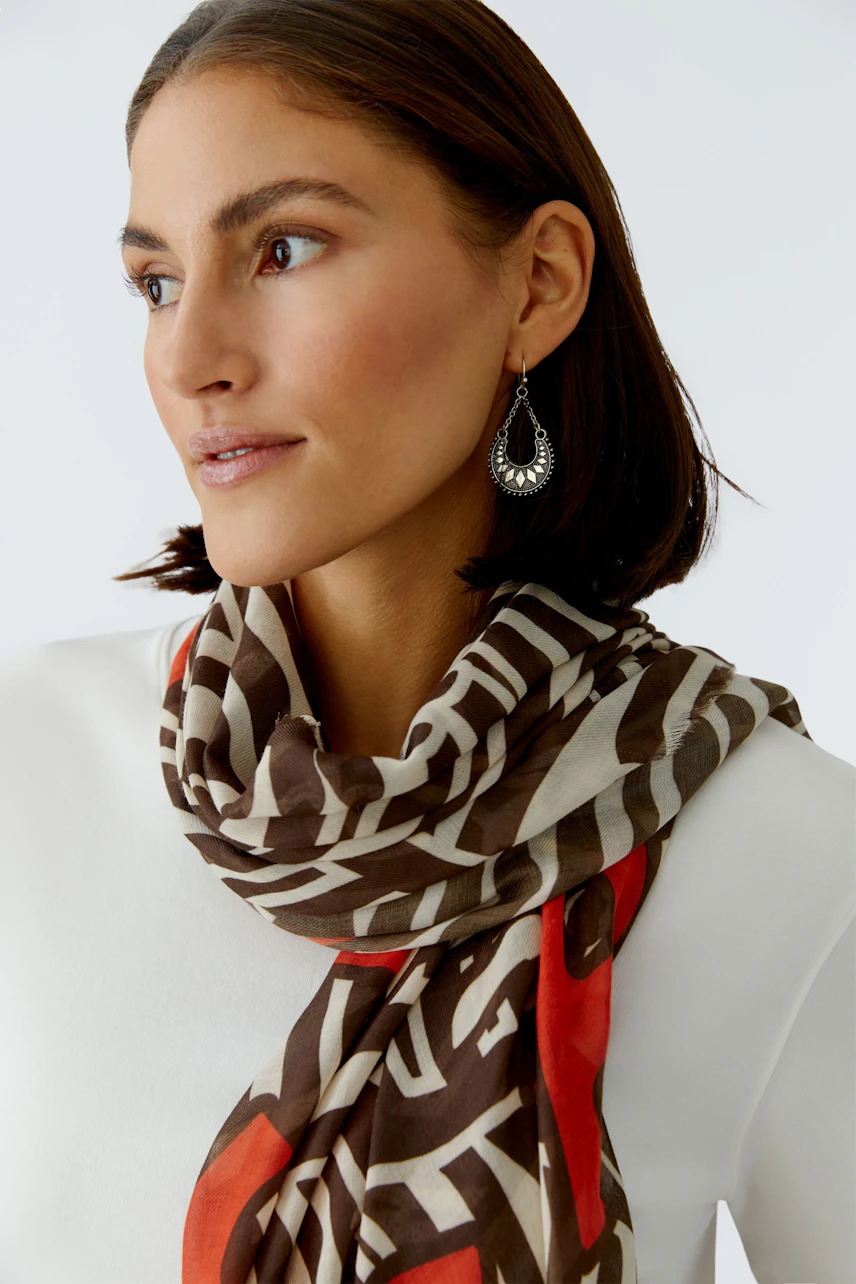 Stylish women's scarf: A woman wearing a patterned scarf with earthy tones, adding a trendy touch.