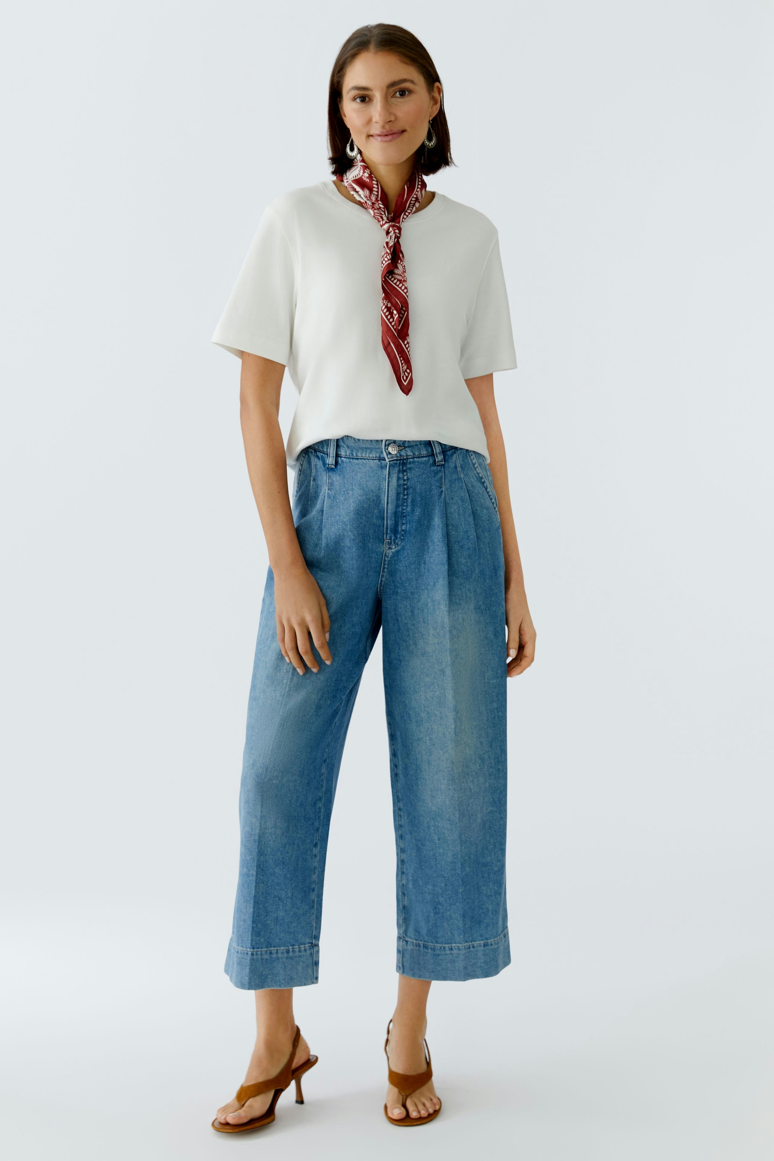 Damen-Tuch: Junge Frau mit rotem Tuch um den Hals, lässig in hellen Jeans und T-Shirt.