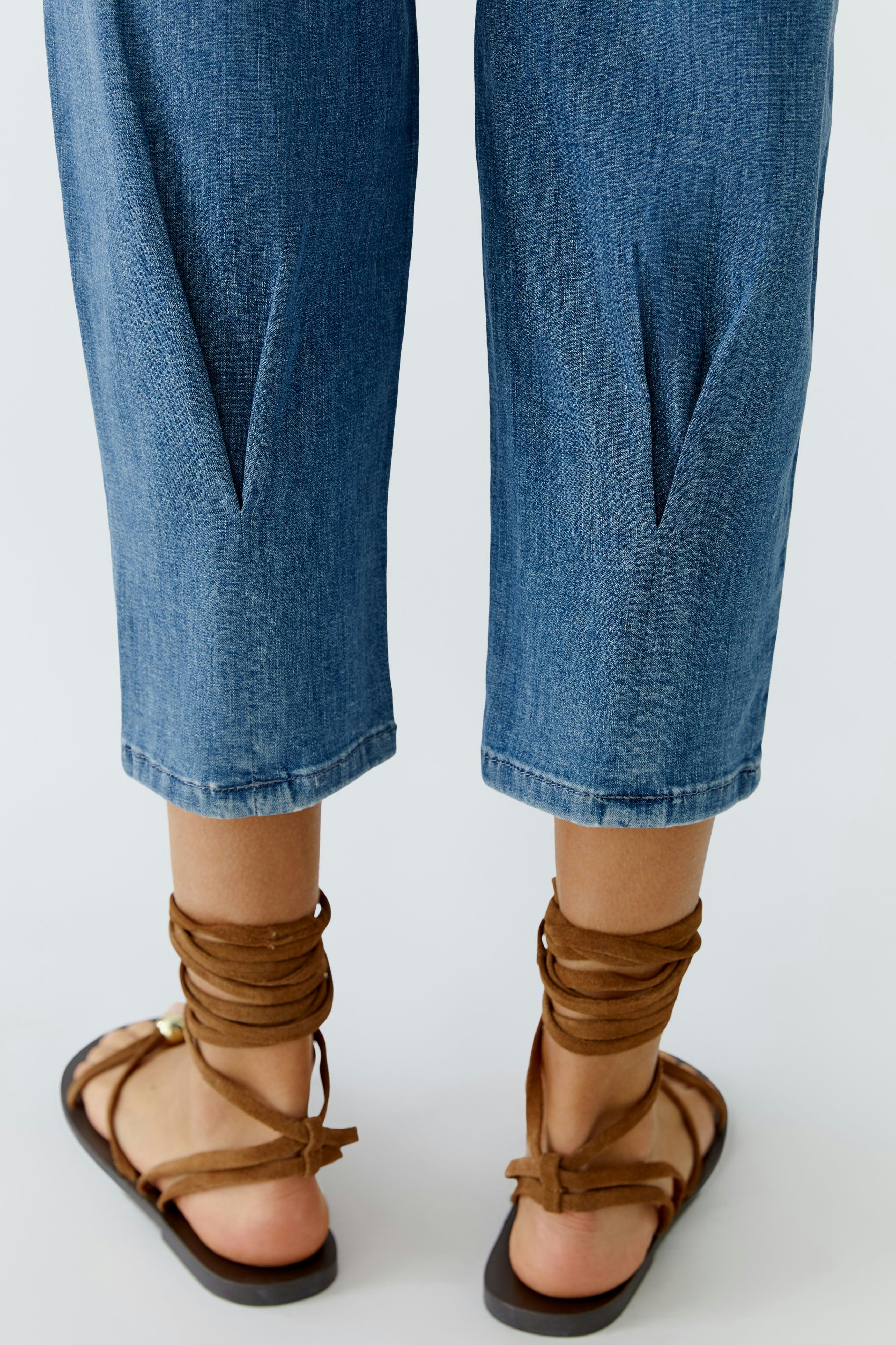 Casual women's jeans: A woman shows off her blue barrel jeans with stylish details and comfortable sandals.