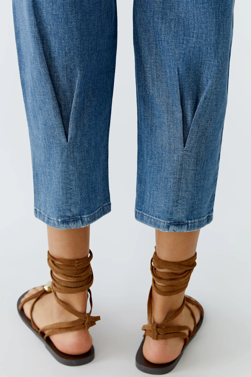 Casual women's jeans: A woman shows off her blue barrel jeans with stylish details and comfortable sandals.