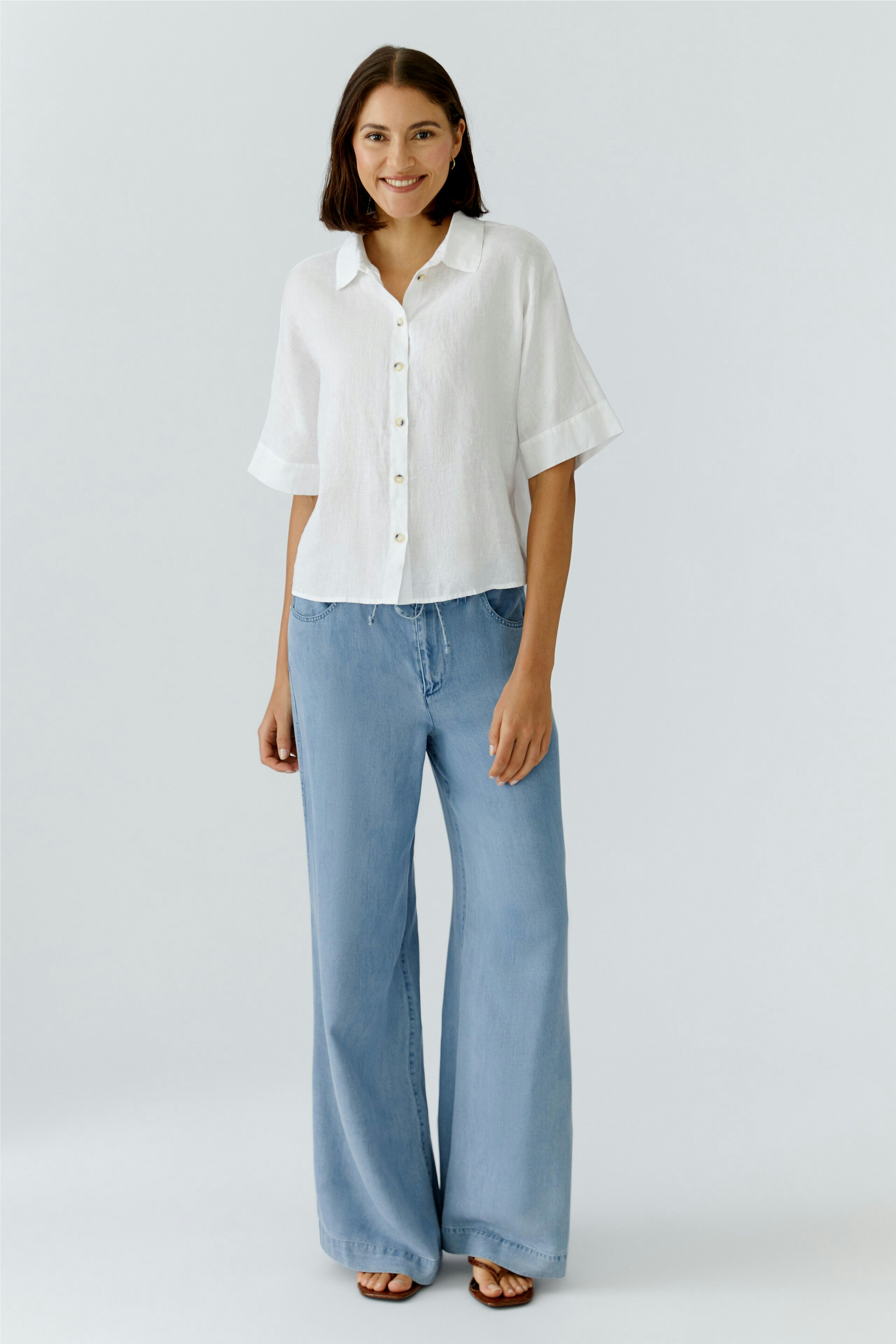 Casual women's pants: Woman in light blue wide-leg pants and white shirt, smiling confidently.