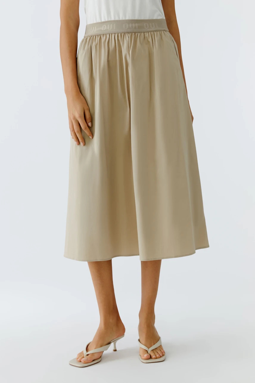 Casual midirock: Woman in a beige midiskirt with an elastic waistband, paired with simple sandals.