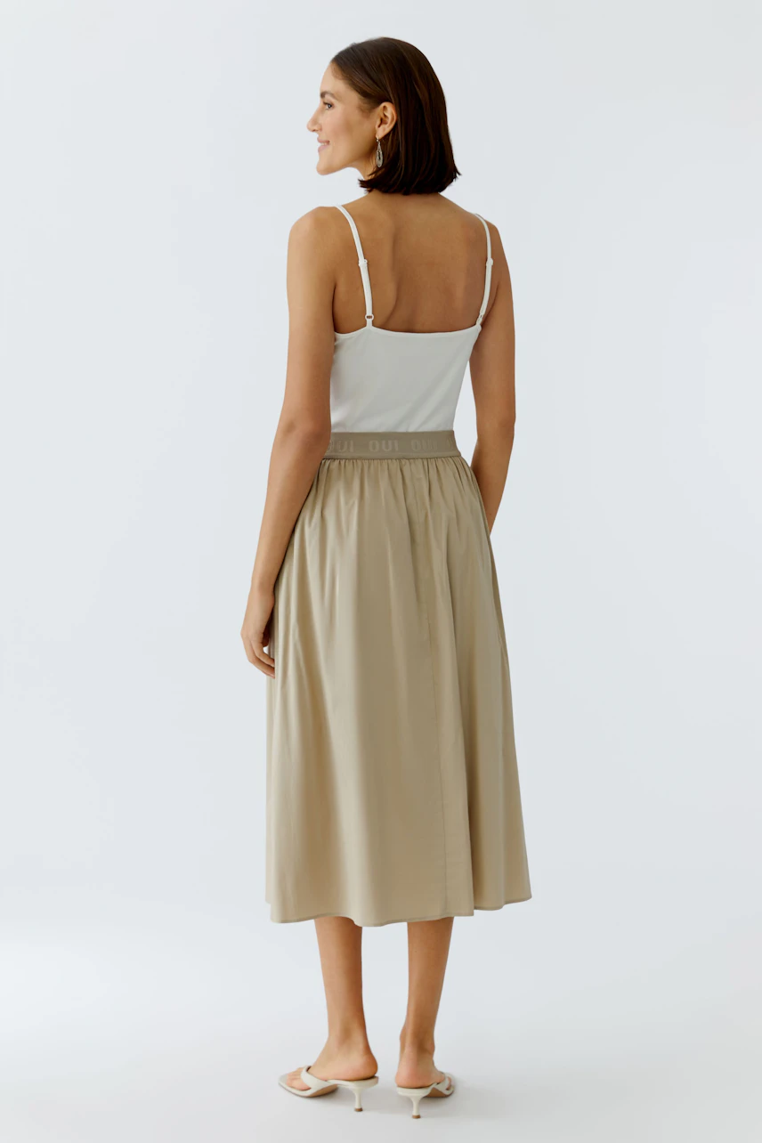 Casual midirock: Woman in a beige skirt with an elastic waistband, showcasing a relaxed fit.