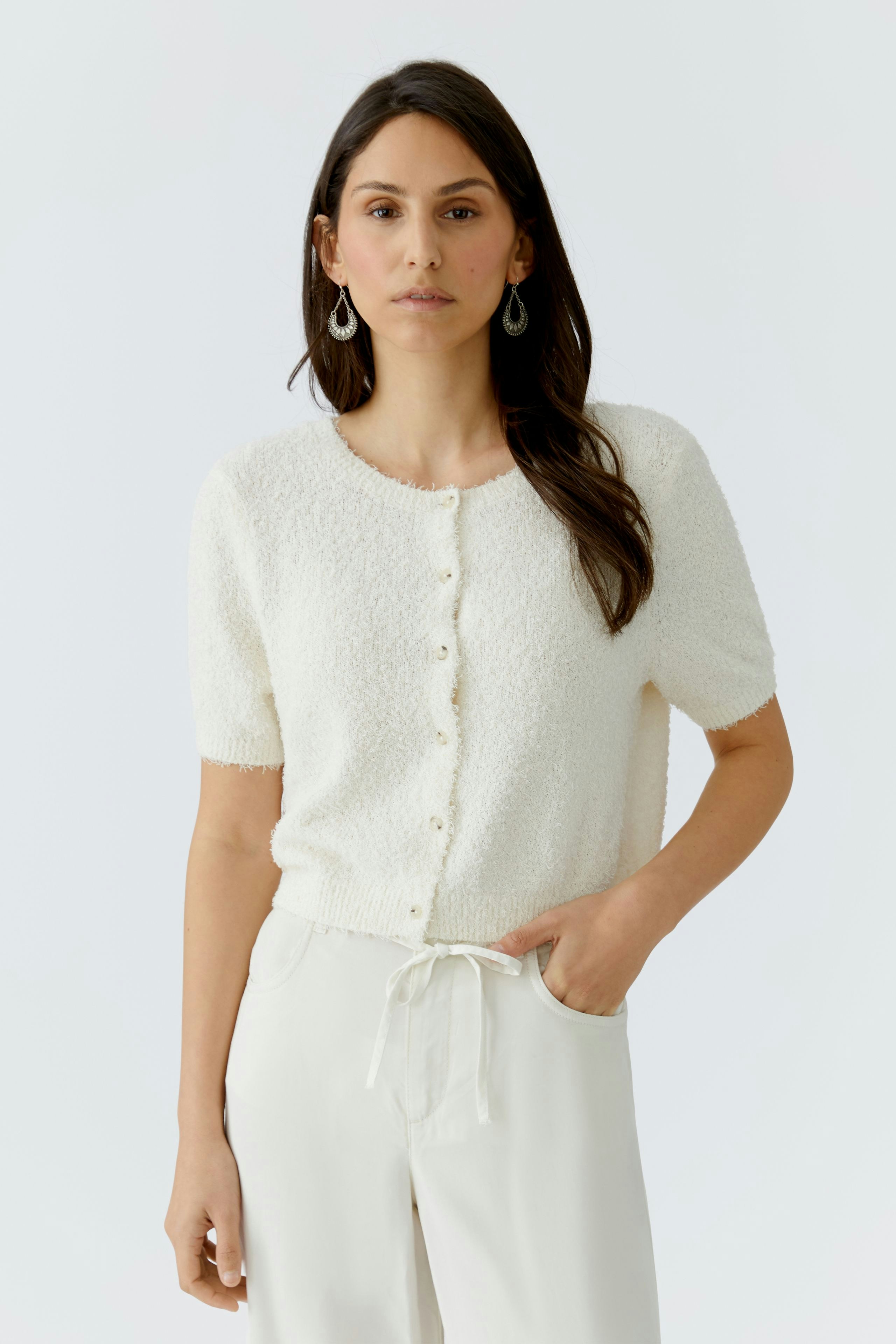 Helle Damen-Strickjacke mit kurzen Ärmeln und Knopfleiste, kombiniert mit lässigen Hosen.