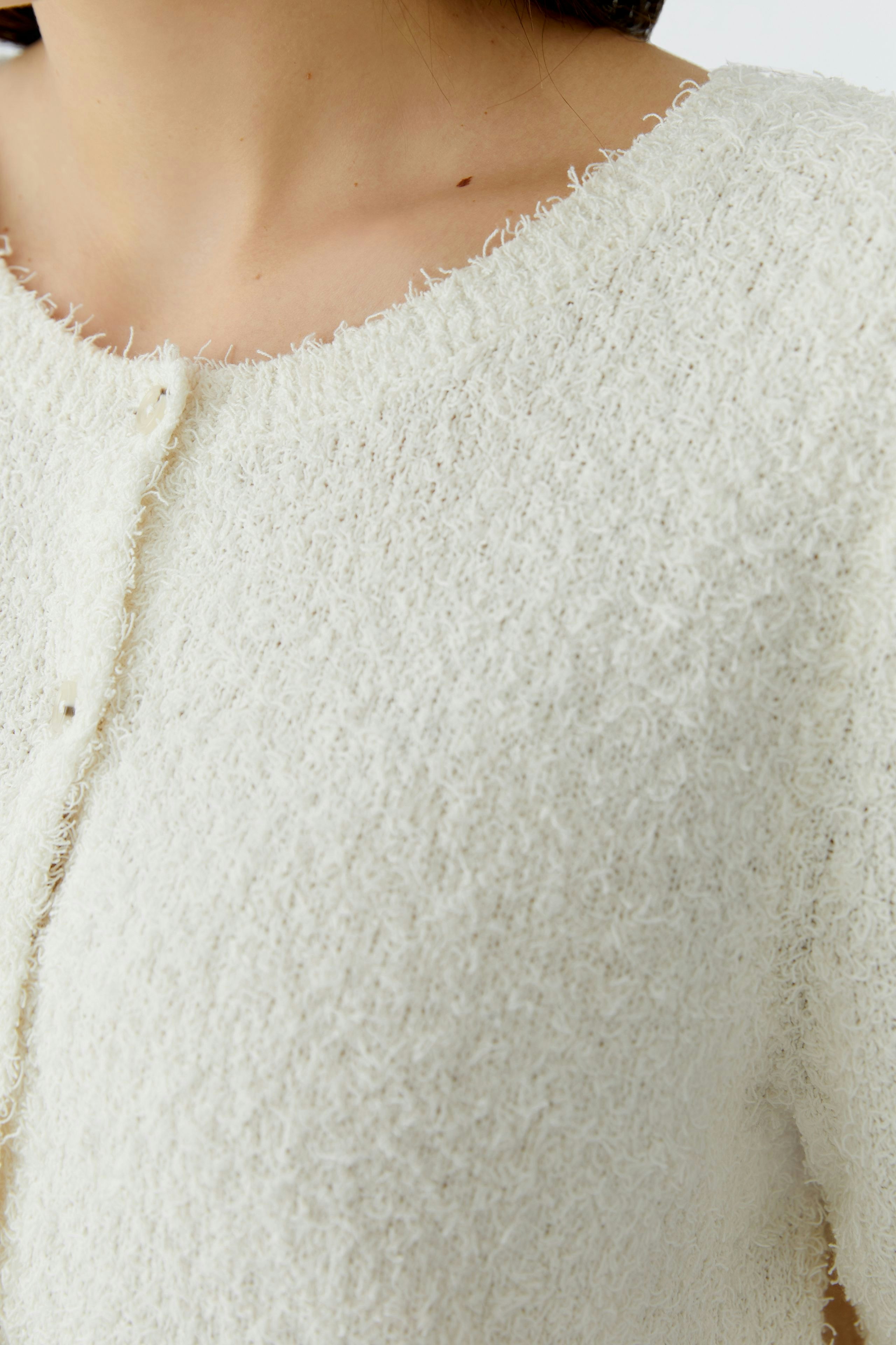 Helle Damen-Strickjacke: Frau mit weicher, strukturierter Jacke in Cremefarbe, ideal für lässige Outfits.