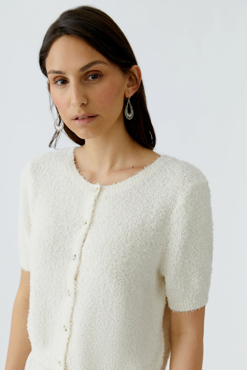 Damen-Strickjacke: Frau in kurzer, weißer Strickjacke mit Knöpfen und lässigem Look.