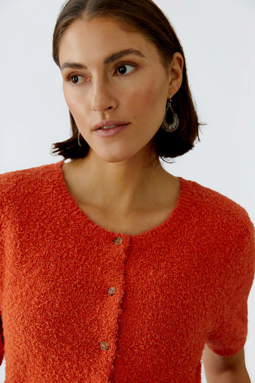 Casual women's cardigan: A woman in a bright orange cardigan with buttons, showcasing a relaxed style.