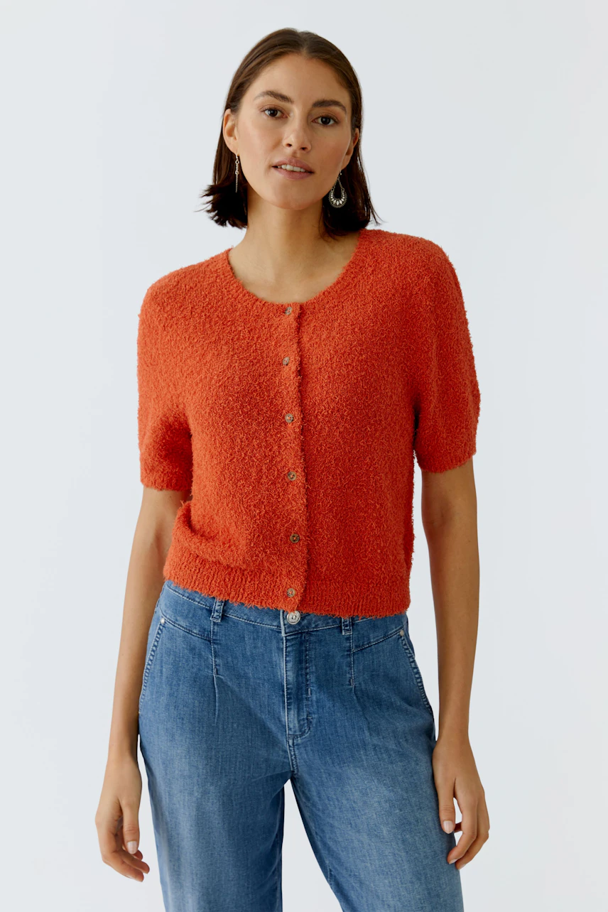 Casual women's cardigan: A woman in a bright orange cardigan with short sleeves and buttons, paired with jeans.