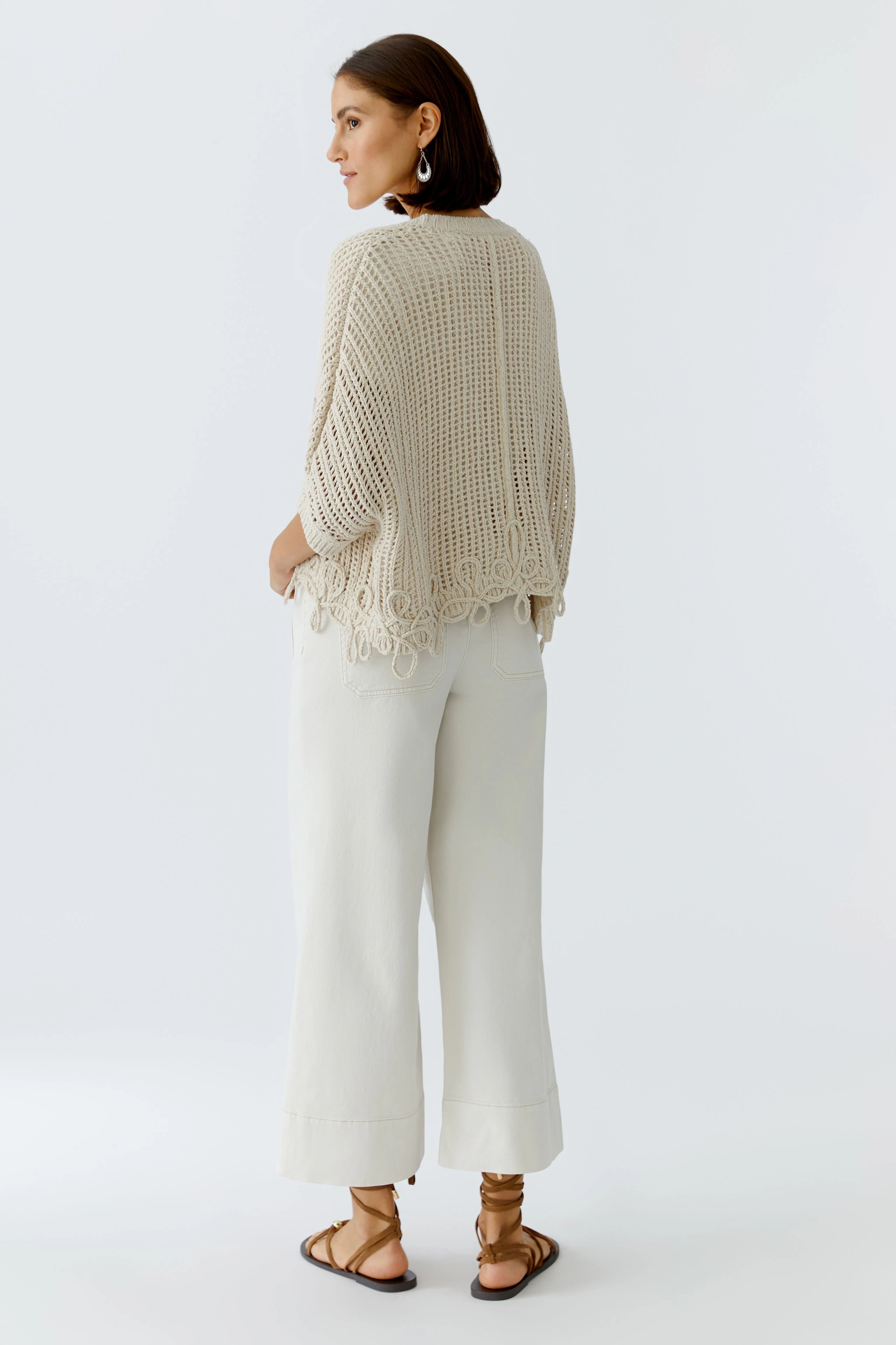 Bequeme Damen-Strickjacke: Frau in heller Strickjacke mit lockerer Passform und fröhlichem Design.