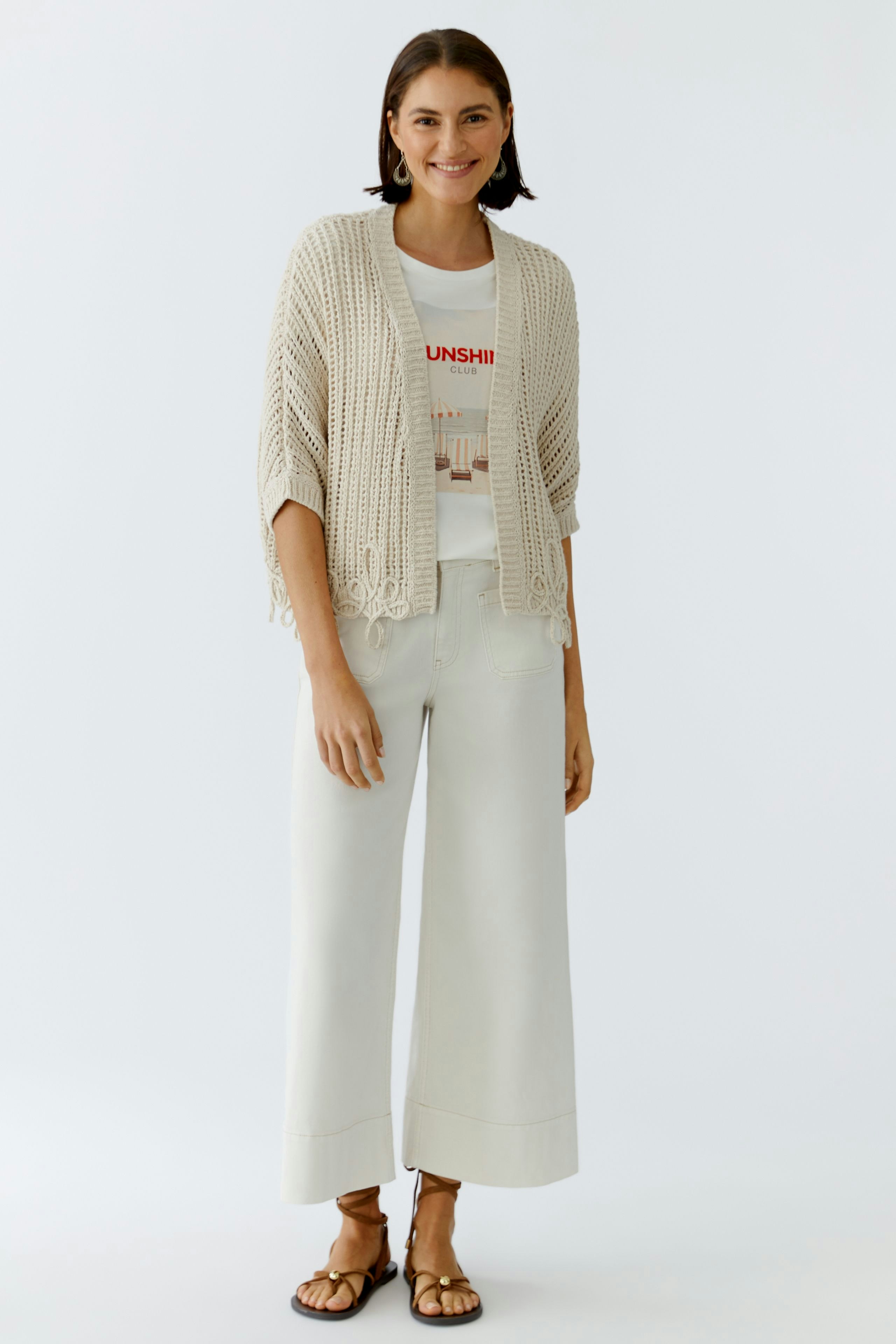 Bequeme Damen-Strickjacke: Frau in heller Strickjacke mit lässigem T-Shirt und weiten Hosen.