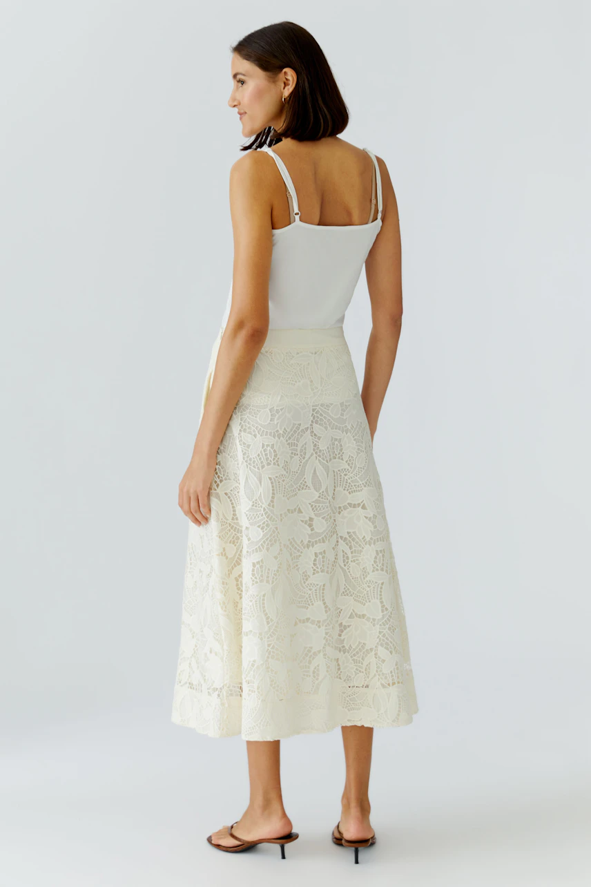 A-line skirt: Woman in a white lace skirt paired with a simple top, showcasing a relaxed style.