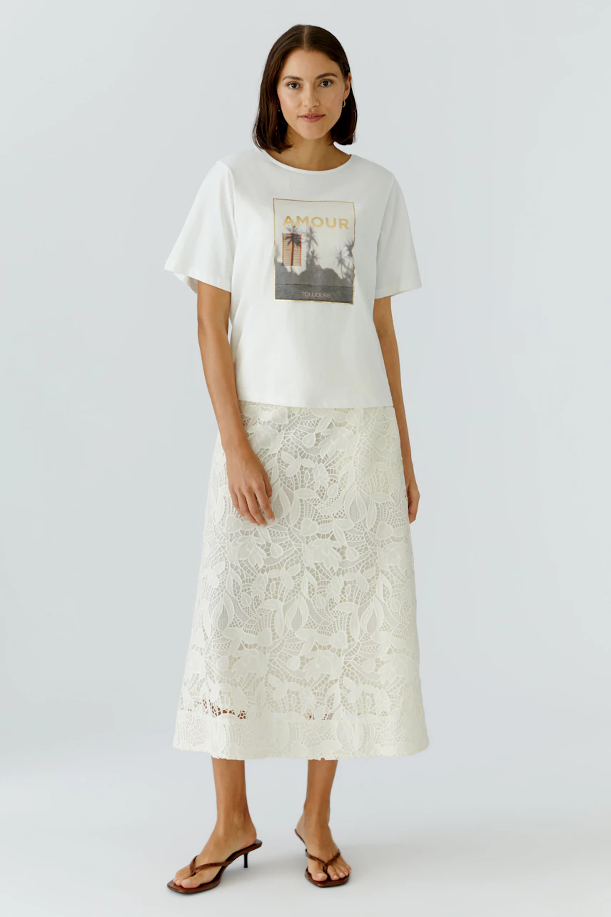 A-line skirt: Woman in a white lace A-line skirt paired with a casual graphic tee.