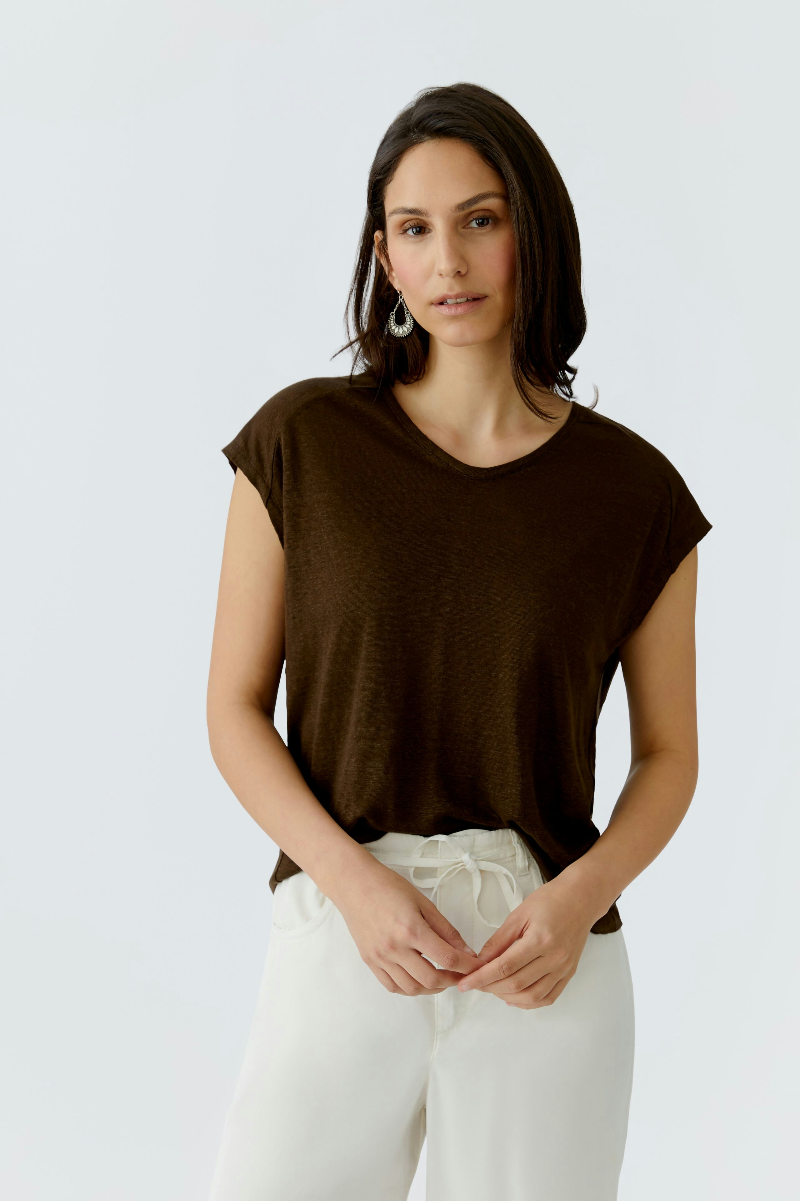 Bequemes Damen-T-Shirt: Frau in braunem T-Shirt mit lässigem Schnitt und weißen Hosen.