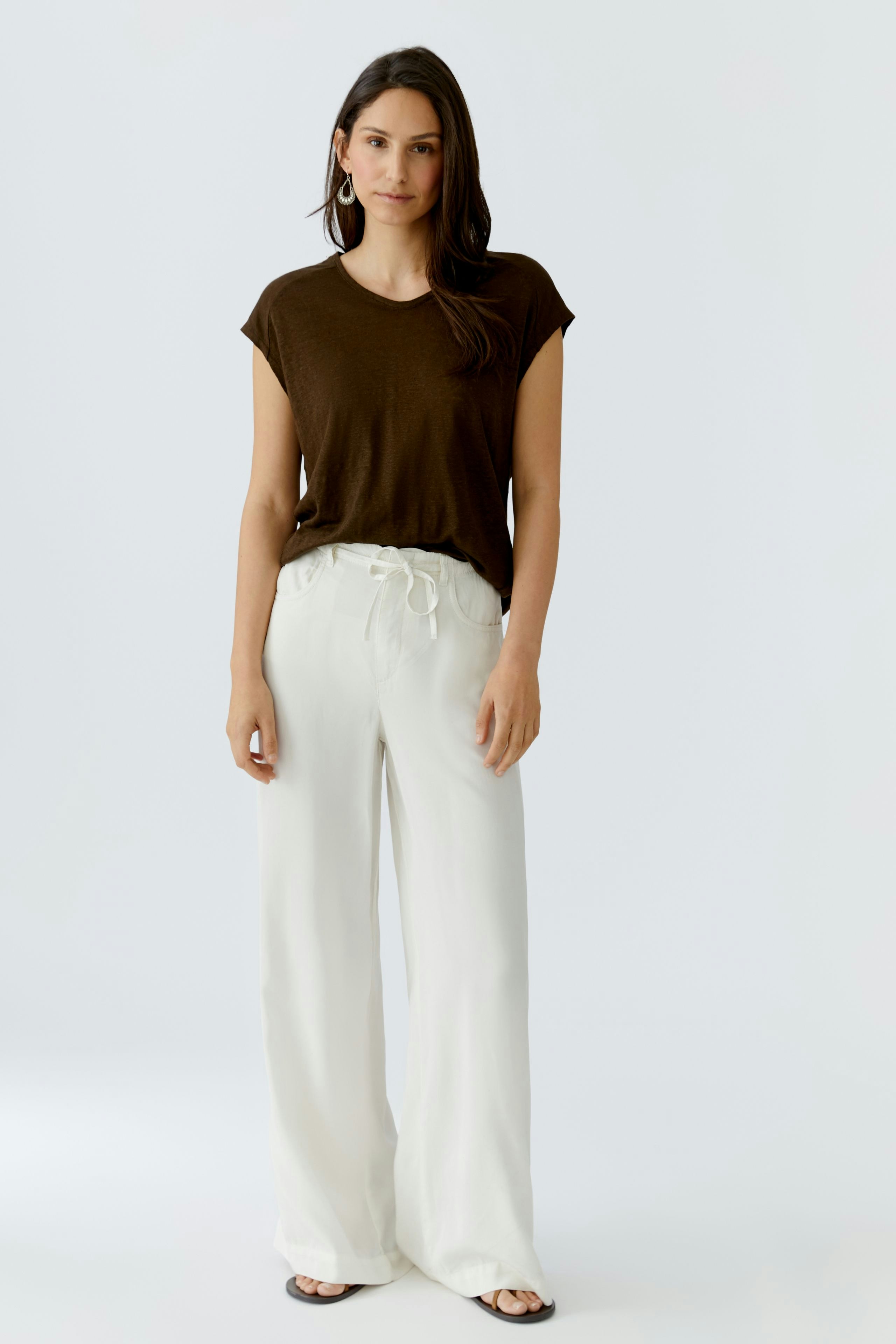 Bequeme Damen-T-Shirt: Frau in braunem T-Shirt mit lässigem Schnitt und weißen, weiten Hosen.