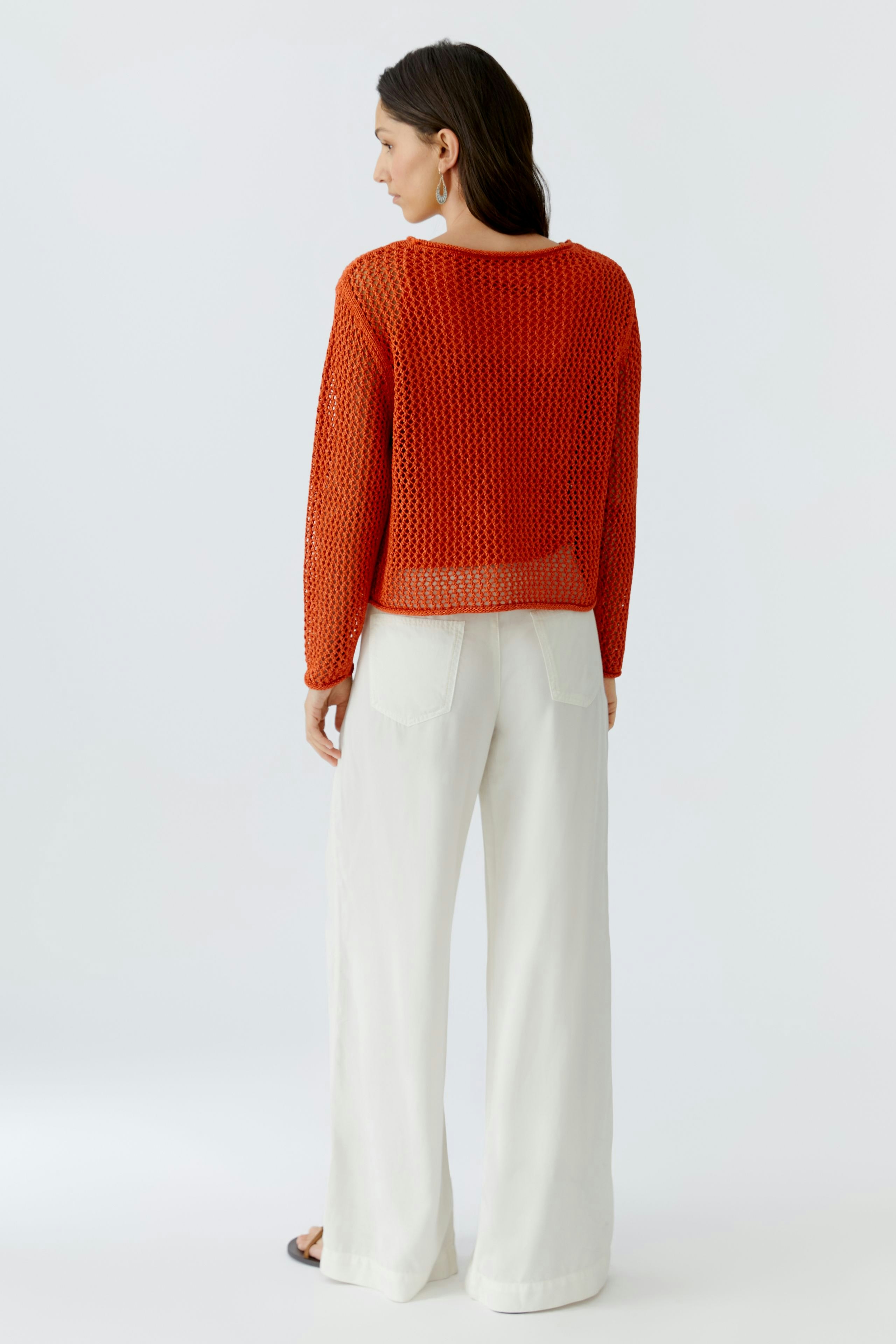 Damen-Pullover: Frau in orangefarbenem, luftigen Strickpullover mit weitem Schnitt und lässigen Hosen.