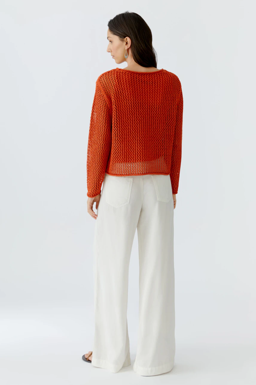 Damen-Pullover: Frau in orangefarbenem, luftigen Strickpullover mit weitem Schnitt und lässigen Hosen.