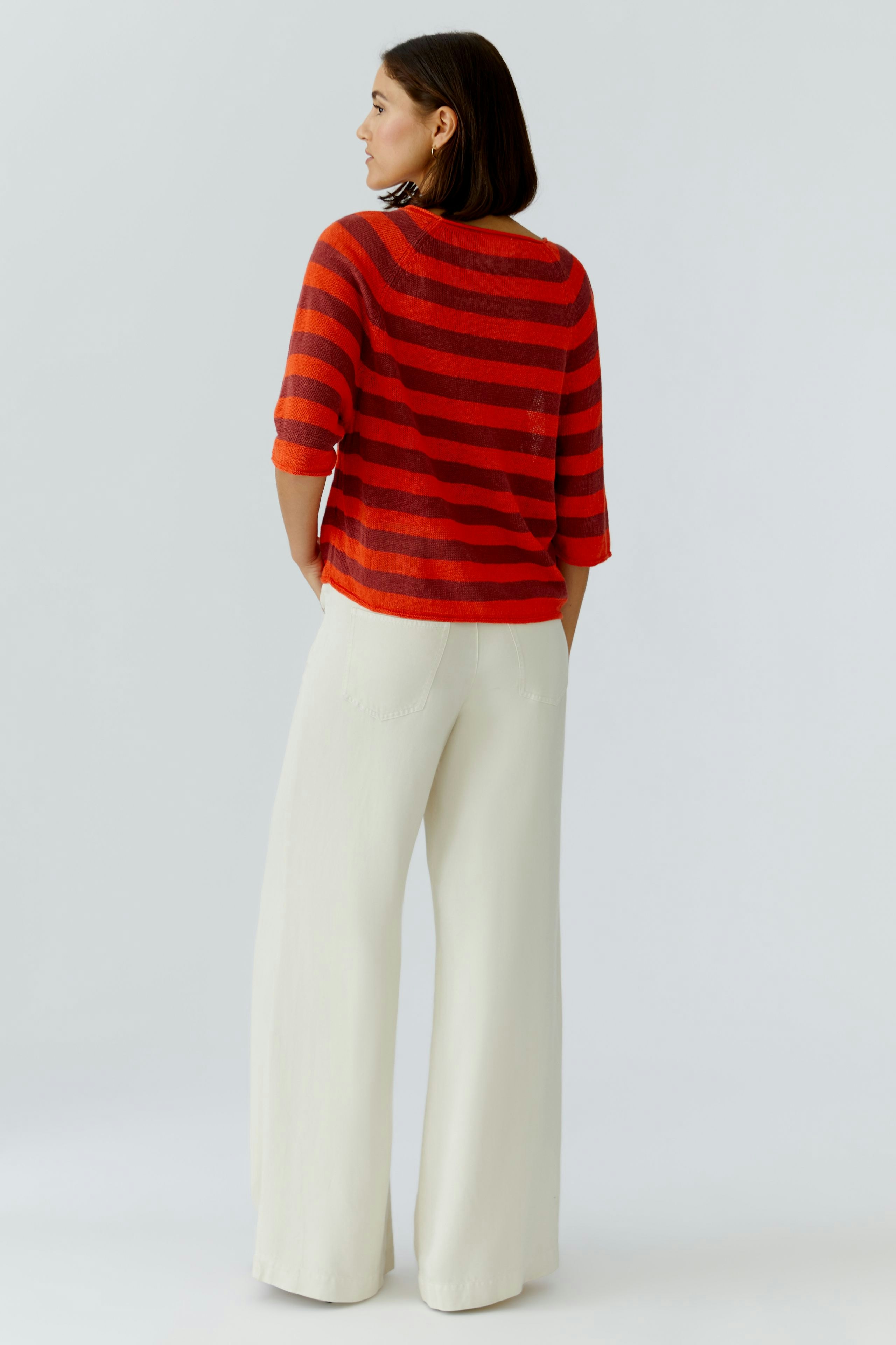 Damen-Pullover: Frau in gestreiftem Pullover mit kurzen Ärmeln und lässigen, weiten Hosen.