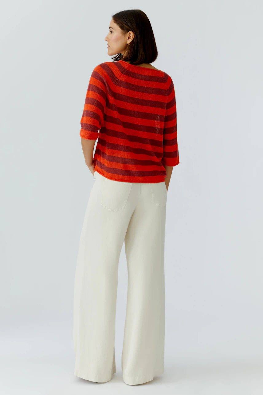 Casual women's pullover: A woman in a red and orange striped pullover with three-quarter sleeves.